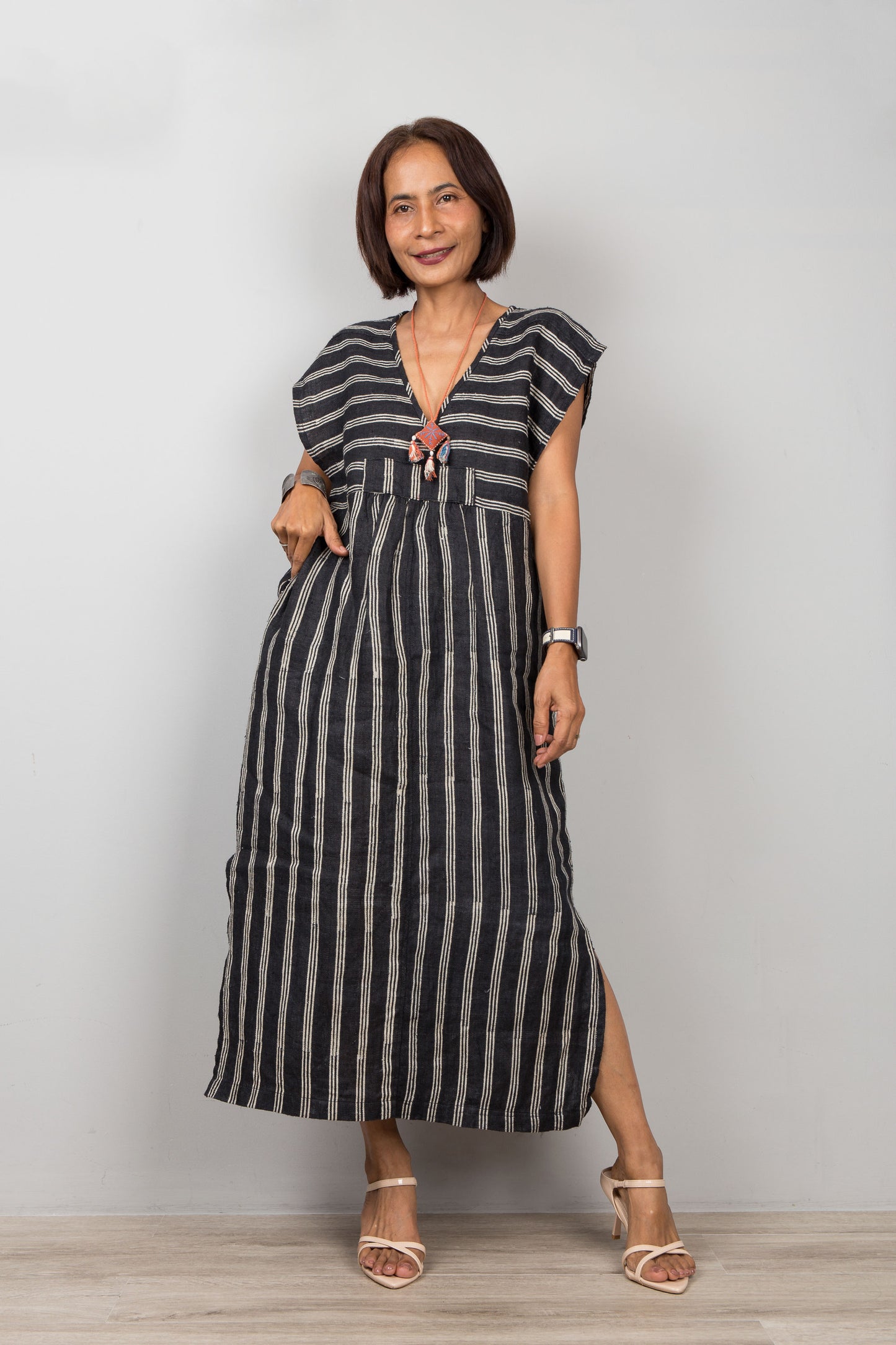 Woman wearing a black and white striped kaftan with short sleeves against a plain background