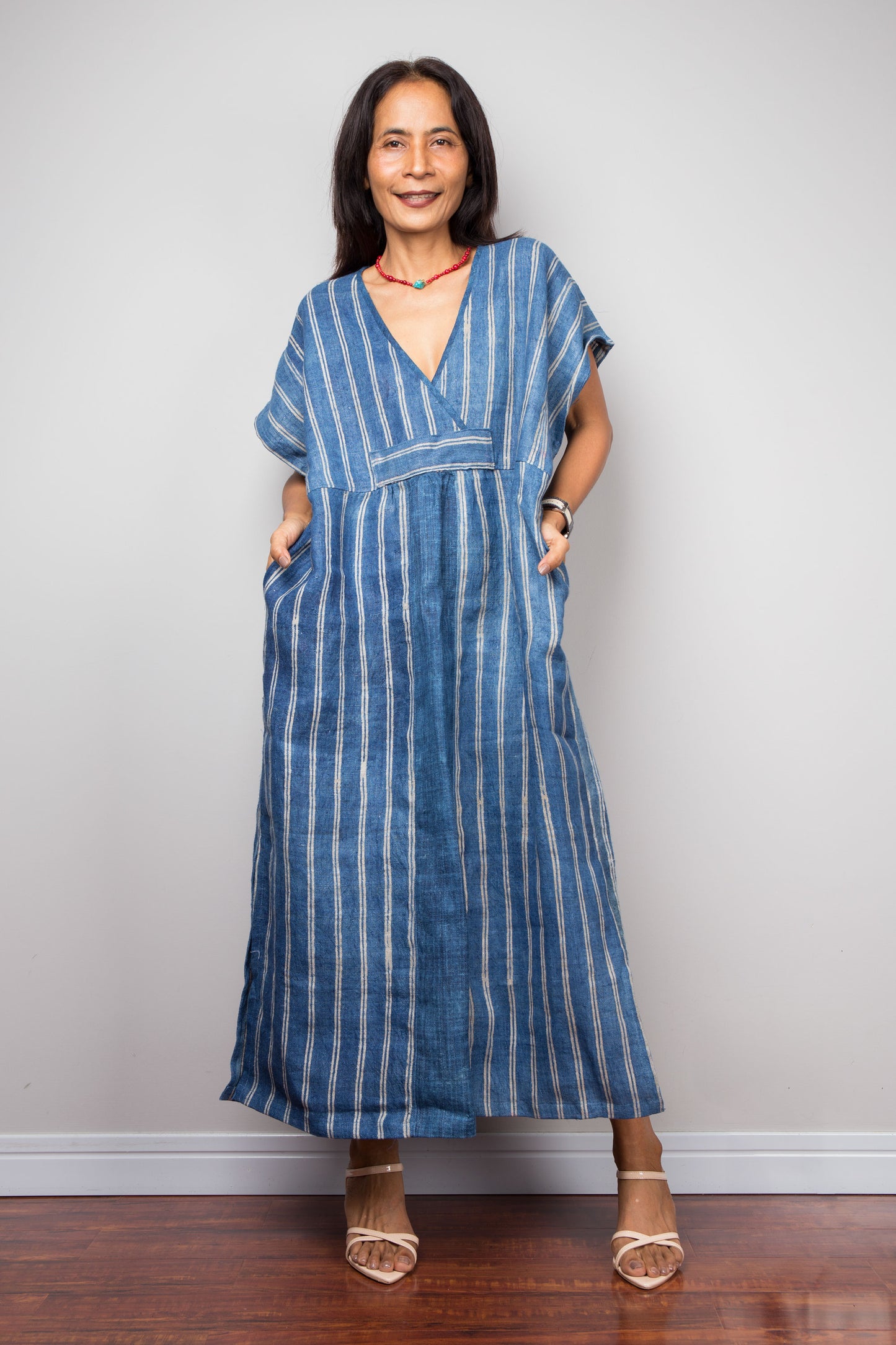 Nuichan wearing a blue striped caftan standing against a plain background