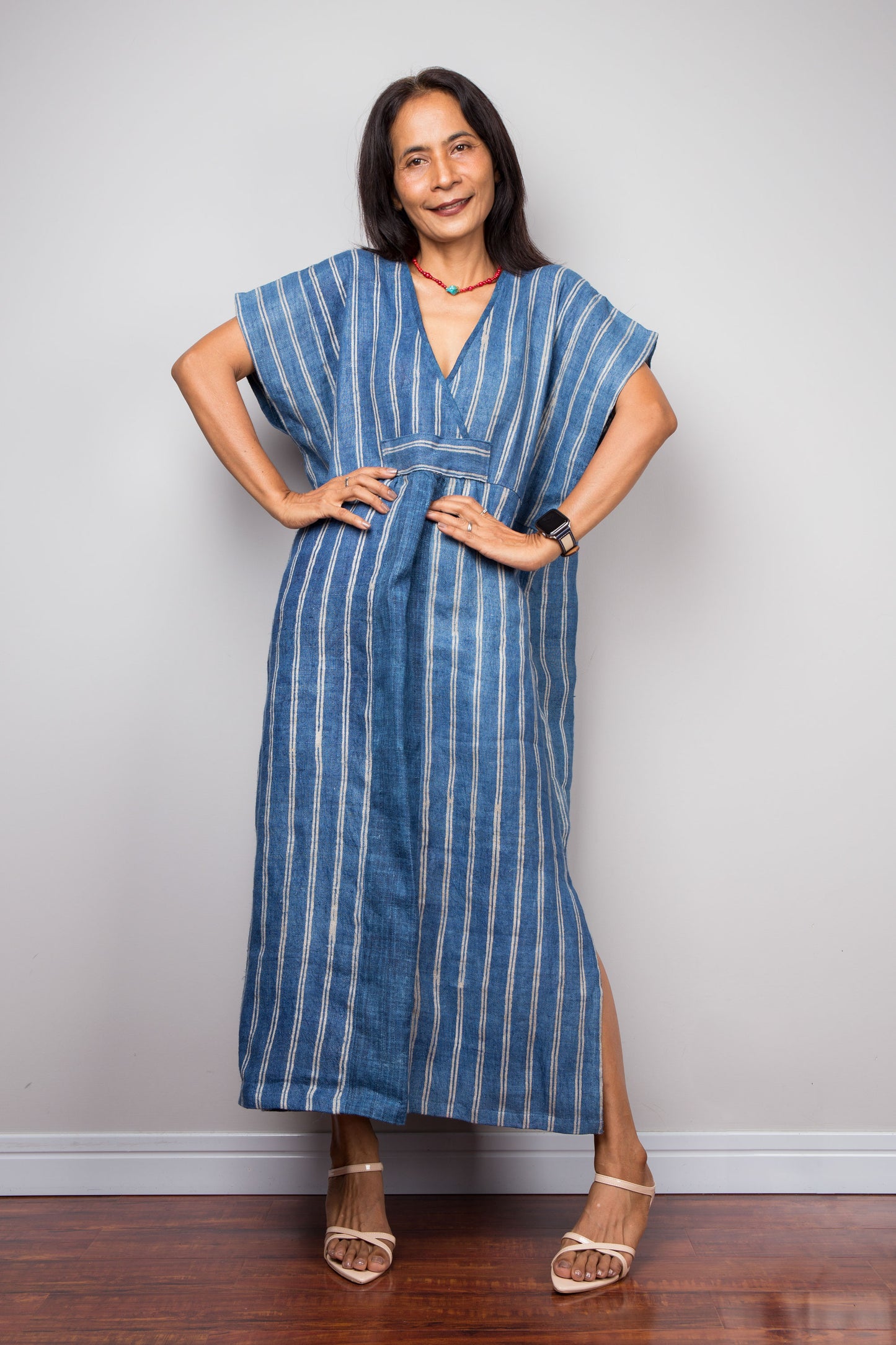 Woman wearing a blue striped dress against a plain background. Nuichan kaftan dress design made from hemp