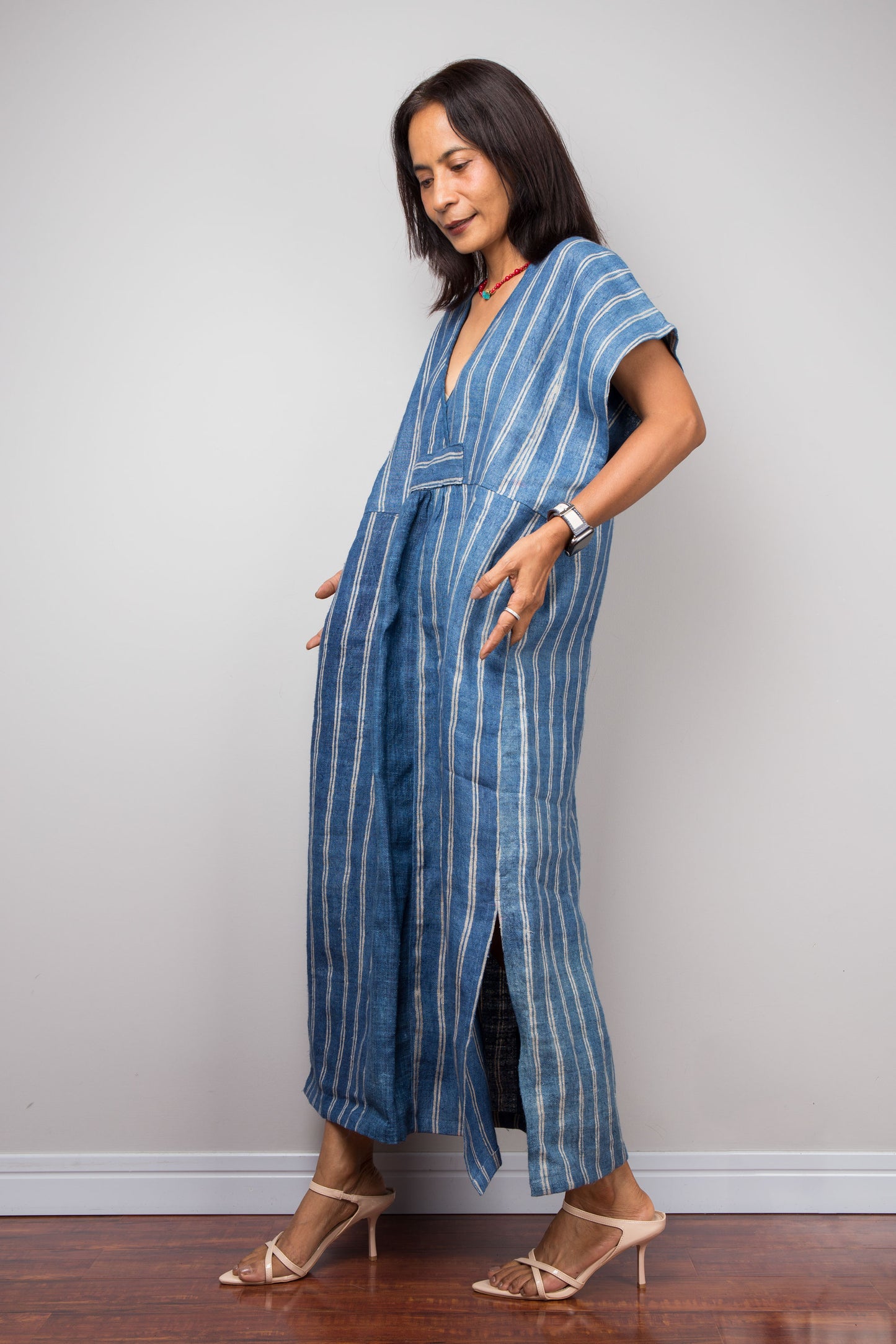 Woman wearing a blue striped caftan against a plain background. Nuichan kaftan design