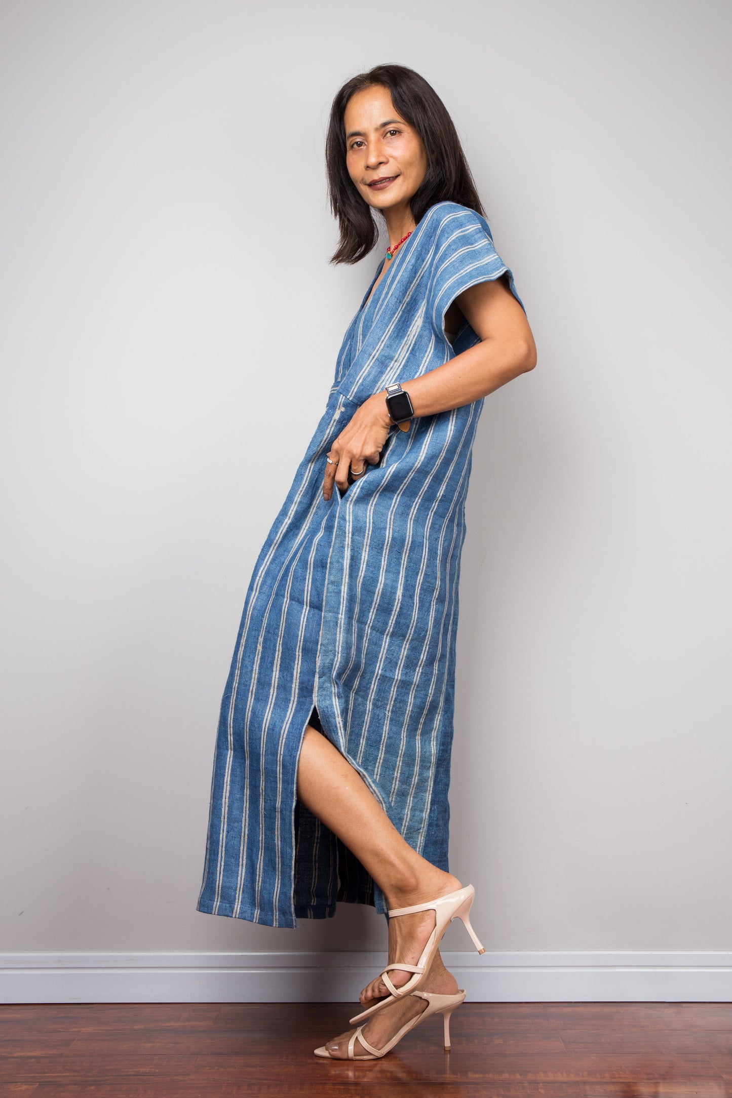Nuichan wearing a blue striped kaftan dress standing against a plain background. Handwoven hemp caftan dress