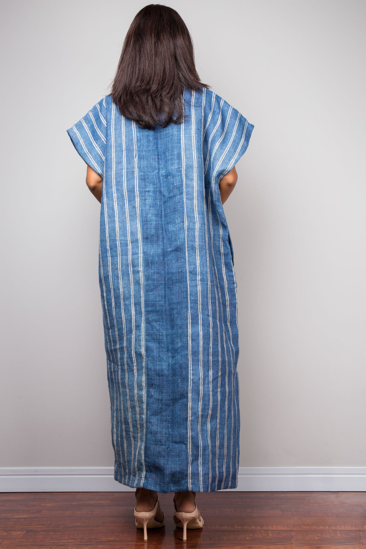 Woman wearing a blue striped Nuichan Caftan dress against a plain background