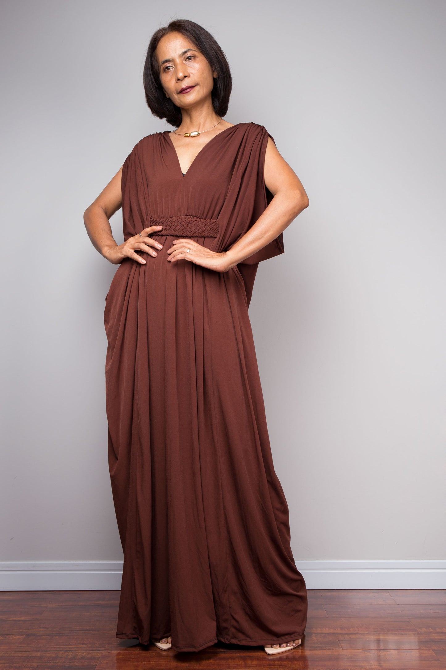 Woman wearing a brown caftan dress against a plain background