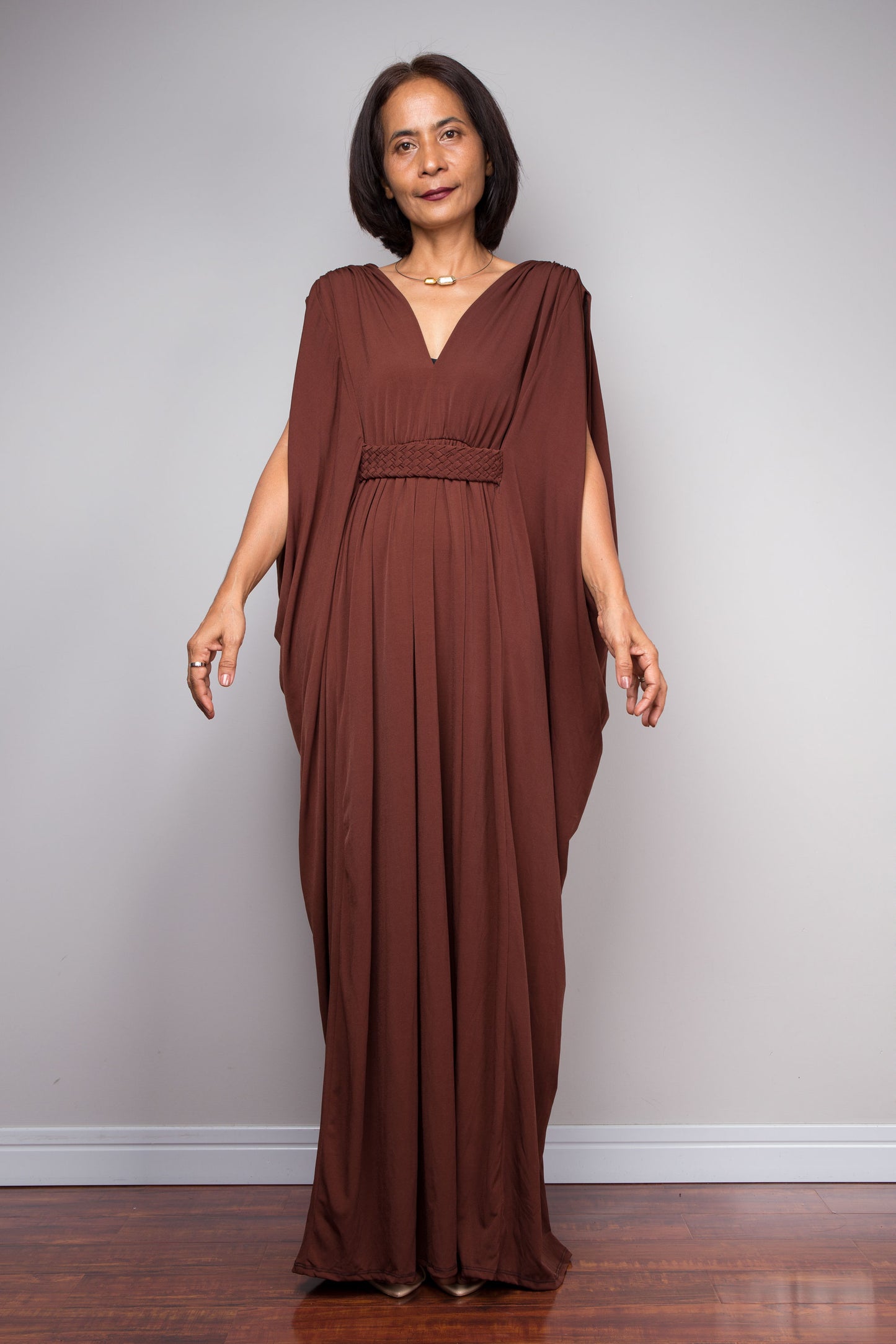 Woman wearing a brown kaftan dress against a plain background