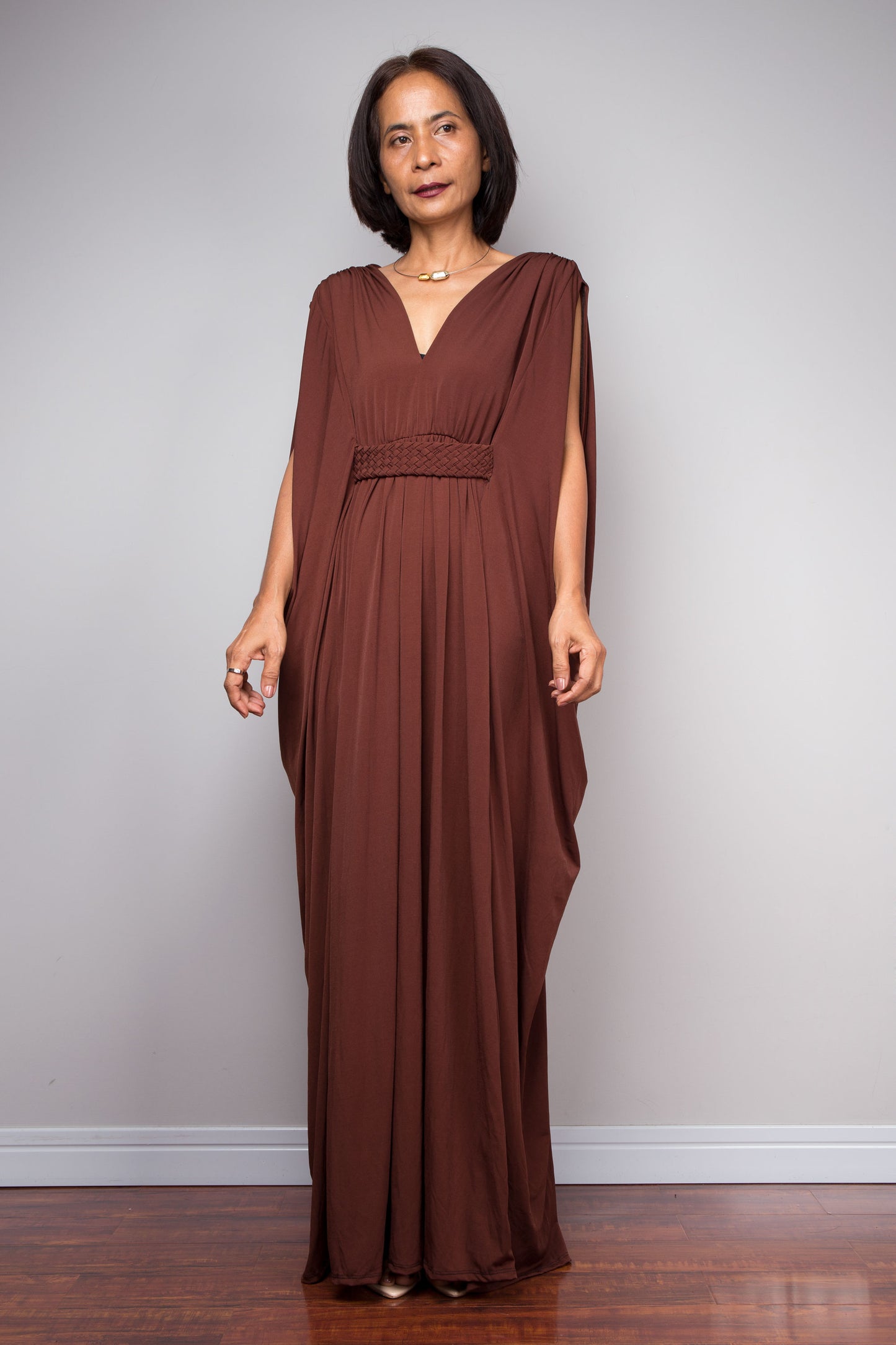 Woman wearing a brown evening gown by Nuichan against a plain background