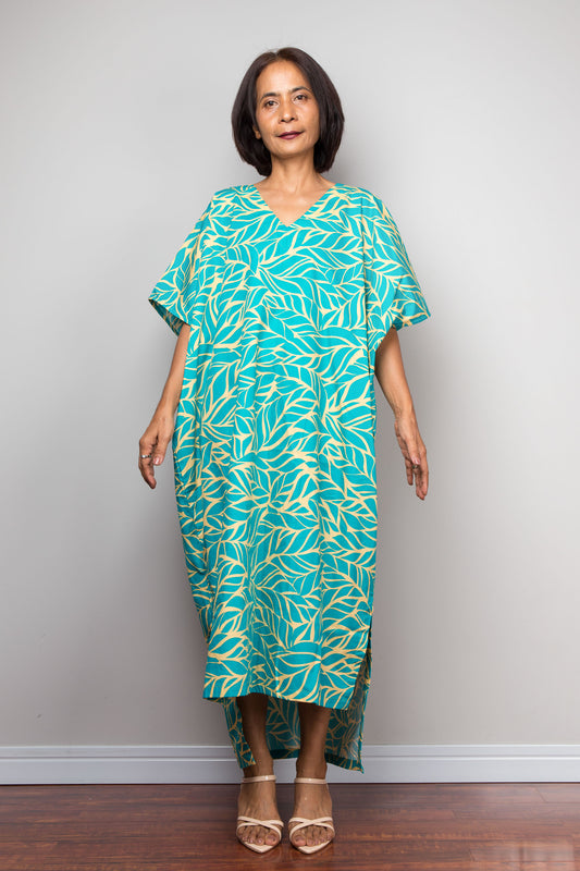 Woman wearing an aqua green and yellow patterned caftan petite dress against a plain background