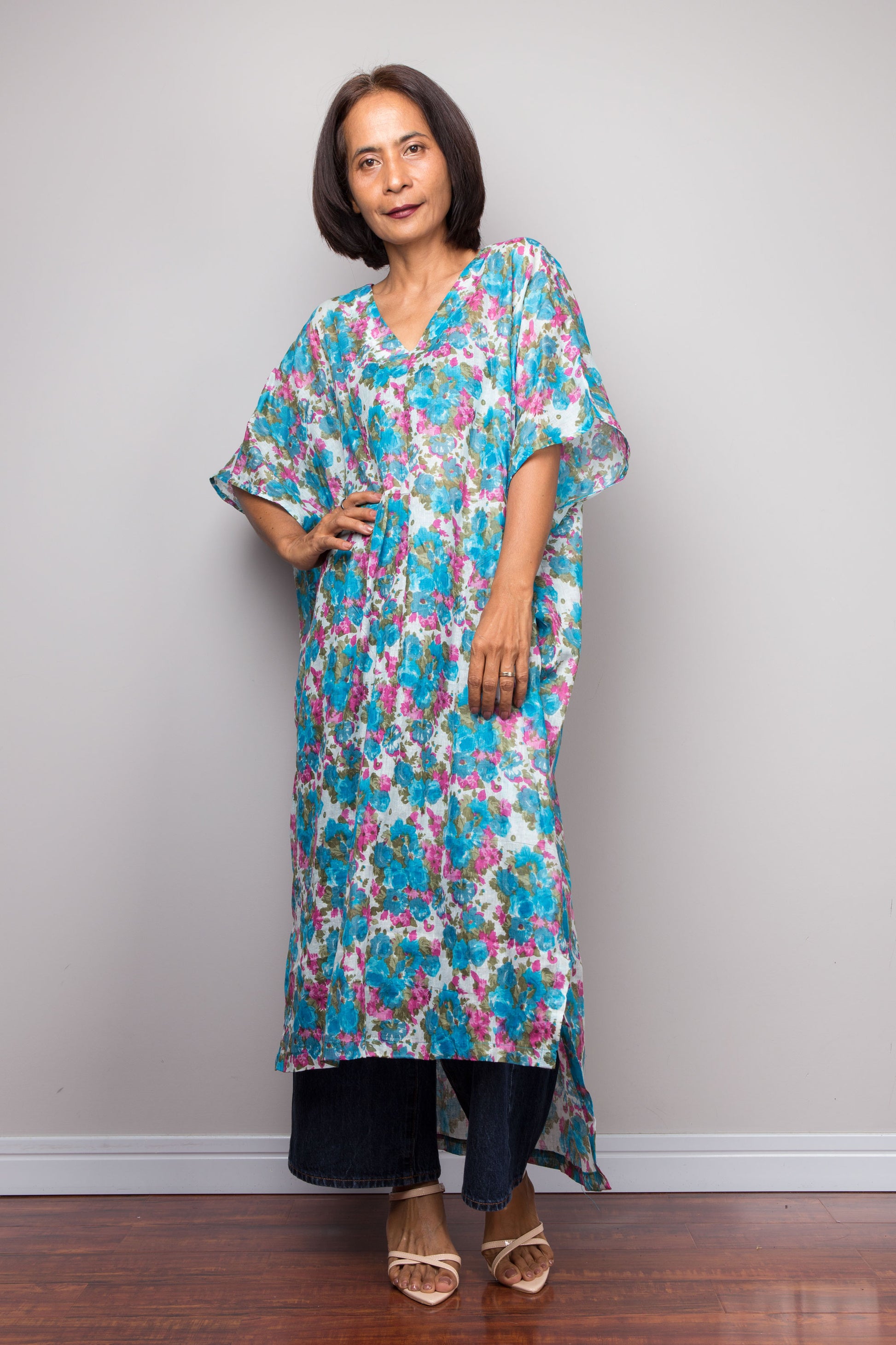 Woman wearing a floral cotton caftan dress against a plain background