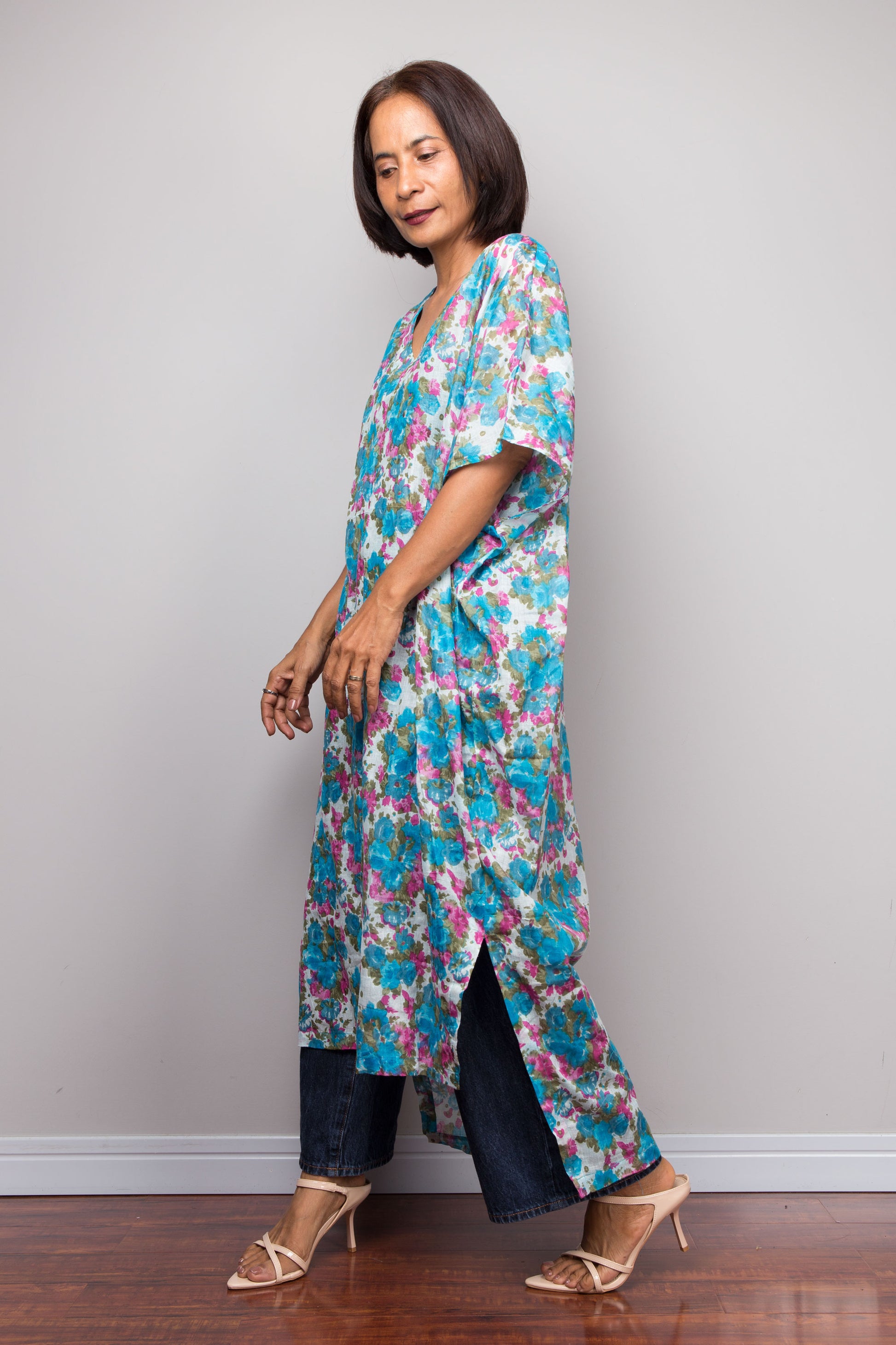 Woman wearing a colorful floral cotton kaftan dress against a plain background