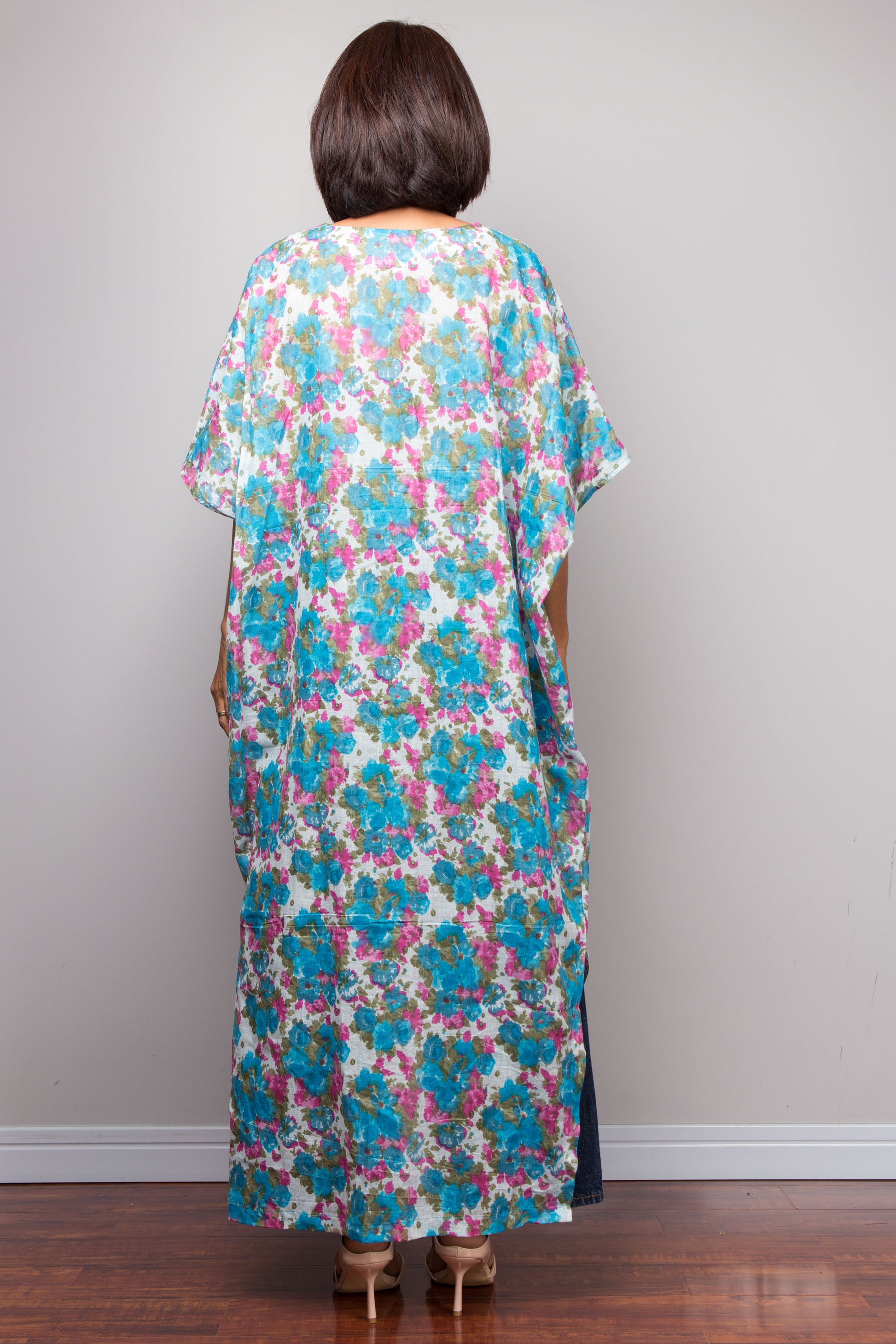Woman wearing a floral cotton caftan dress with a plain background.  Petite short front dress.