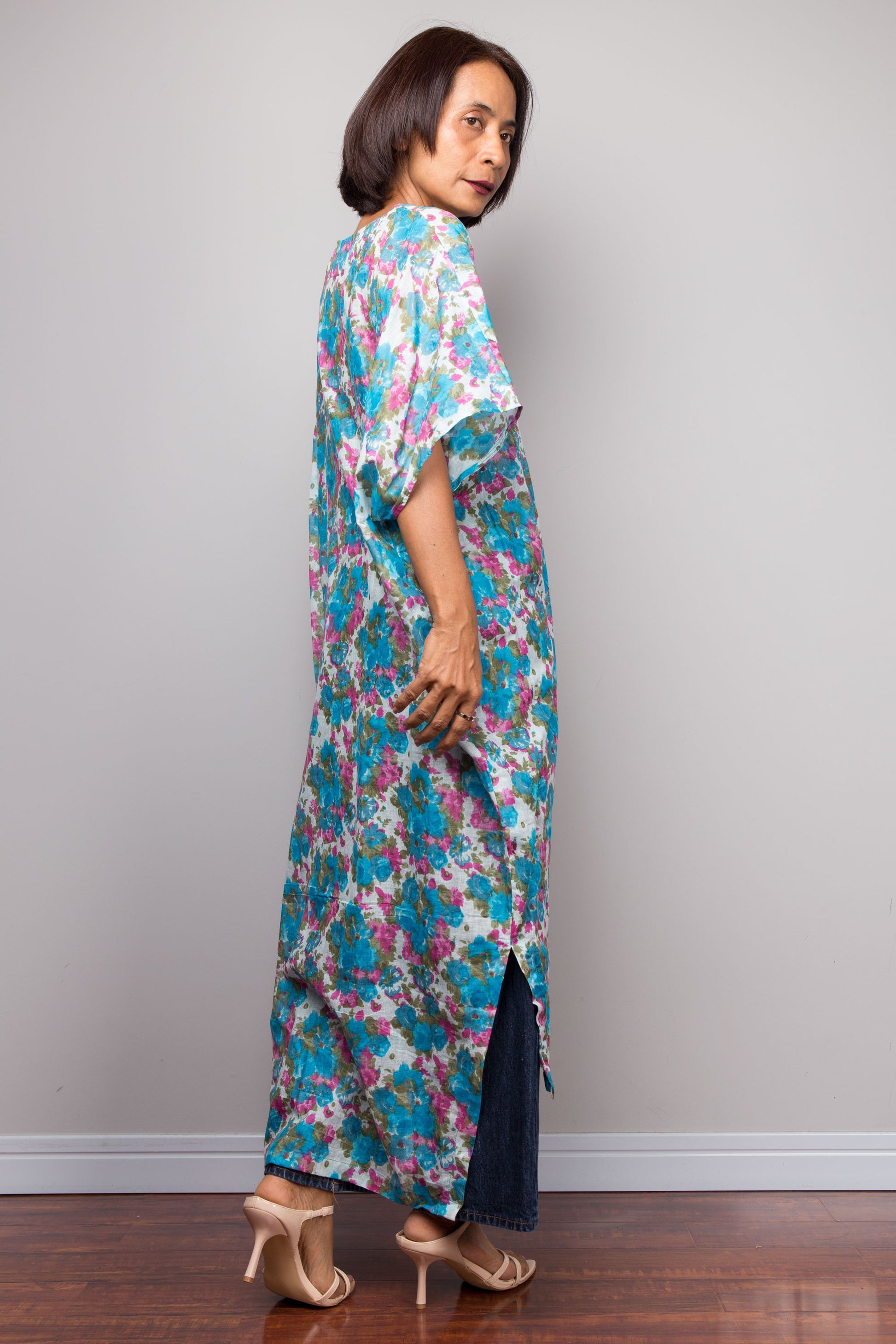 Woman wearing a colourful cotton caftan dress against a plain background