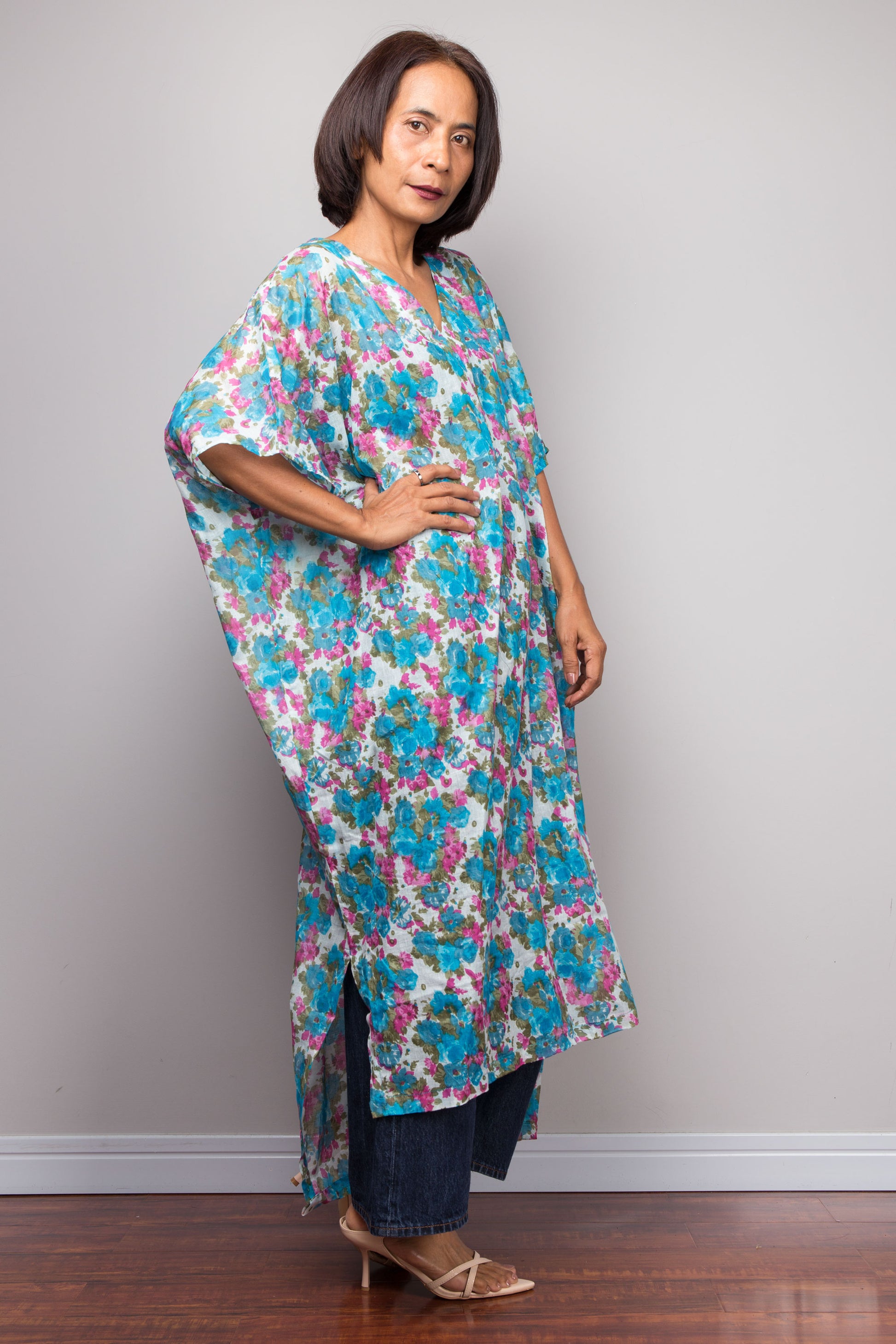 Petite Woman wearing a colourful floral dress against a plain background