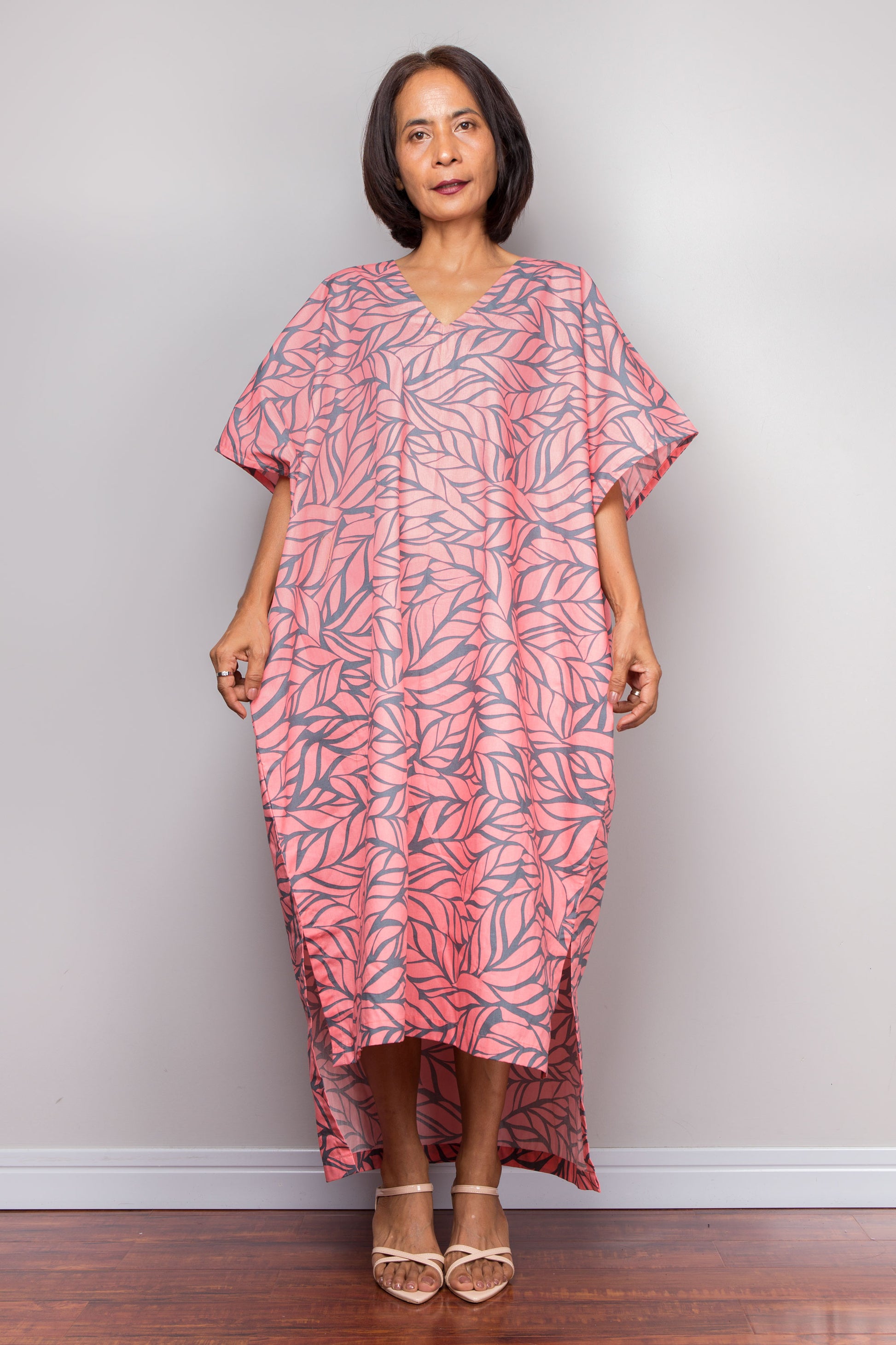 Petite Woman wearing a pink and grey patterned caftan dress against a plain background