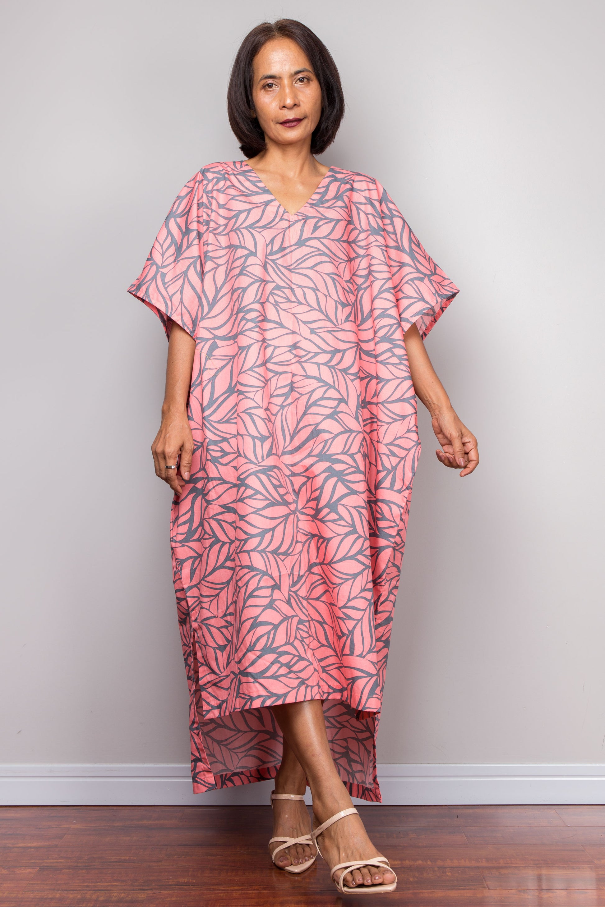 Woman wearing a pink leaf-patterned kaftan against a plain background