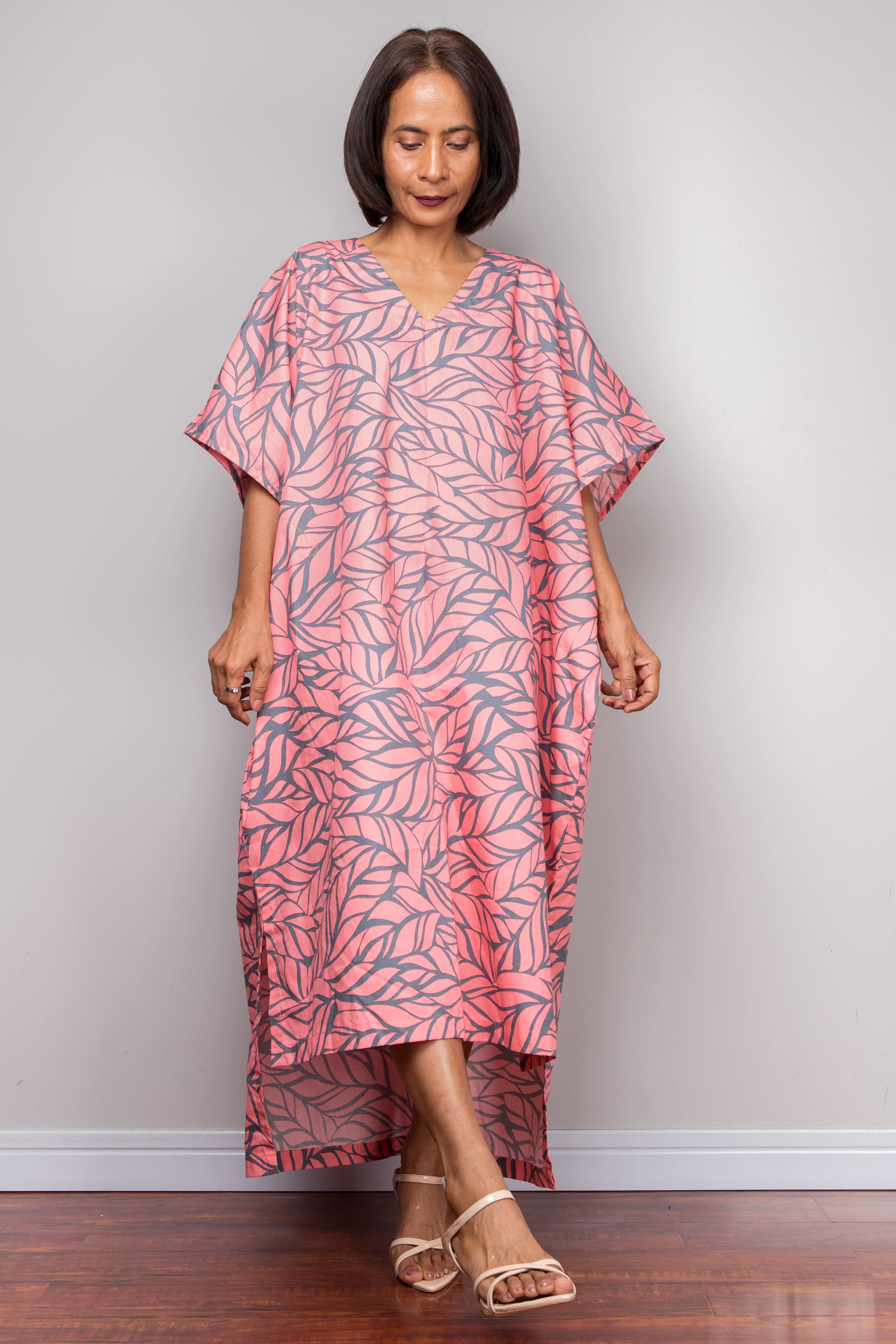 Petite Woman wearing a pink leaf-patterned boho caftan dress against a plain background