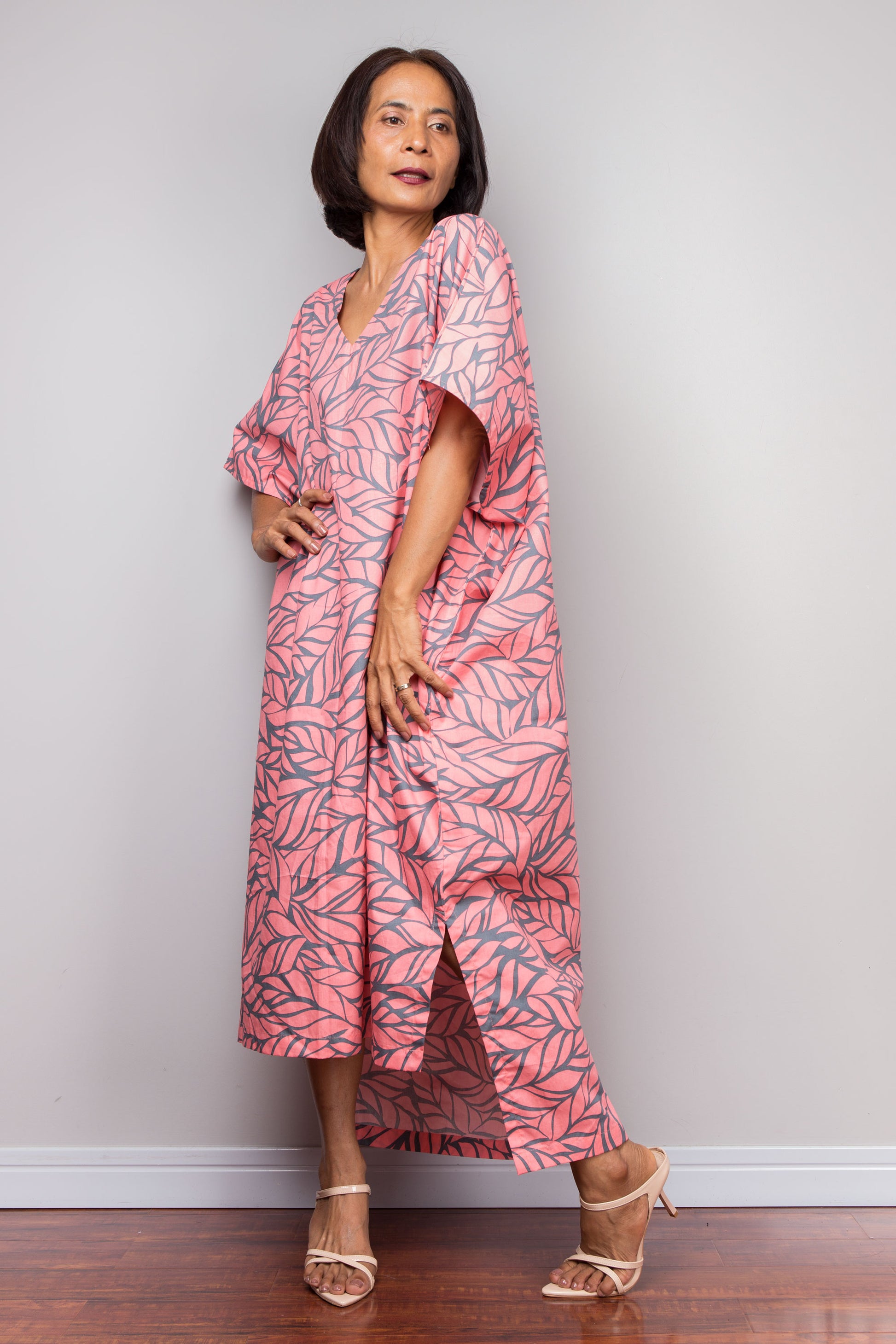 Woman wearing a pink cotton caftan dress standing against a plain background