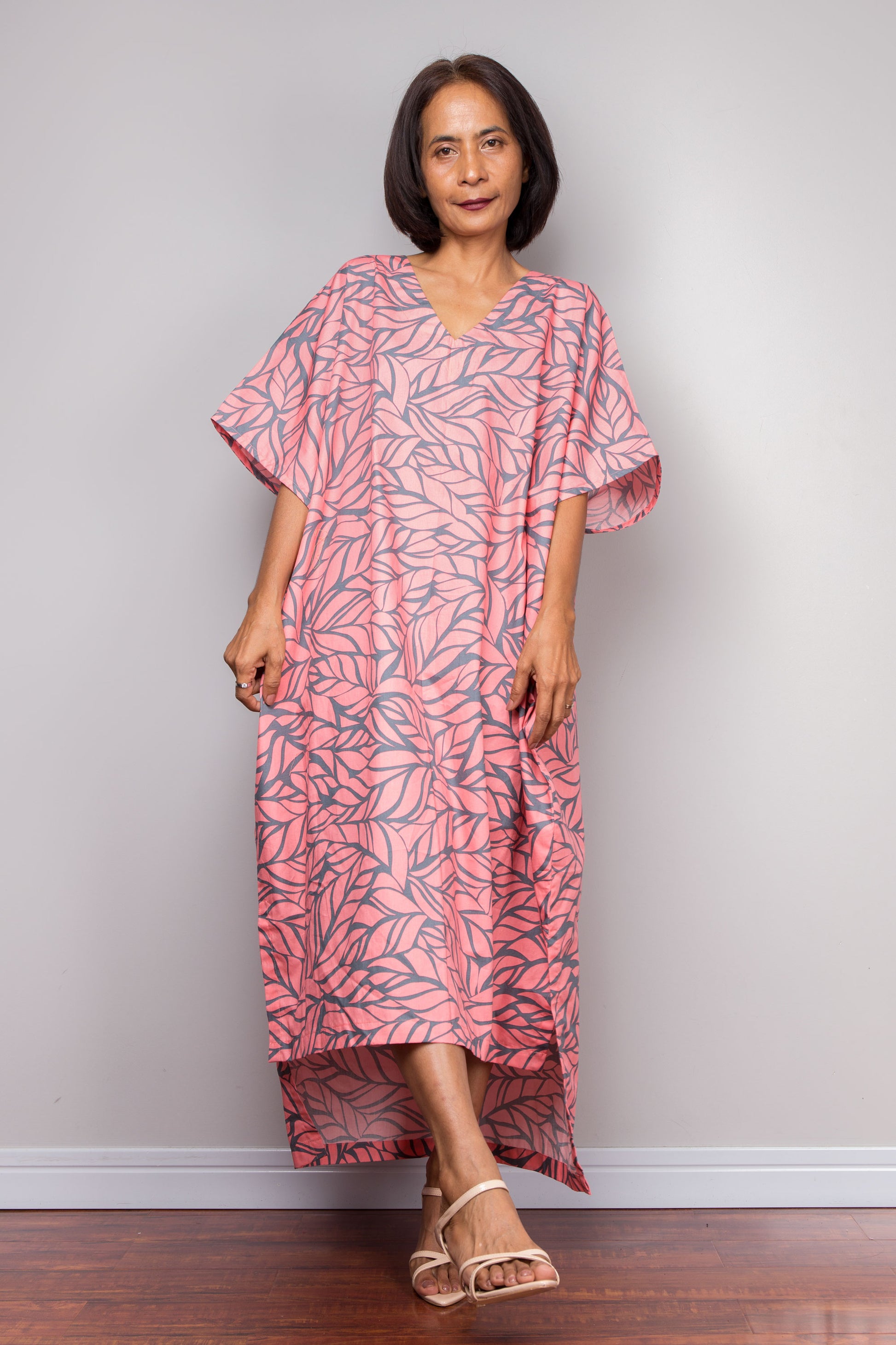 Woman wearing a pink kaftan dress against a plain background