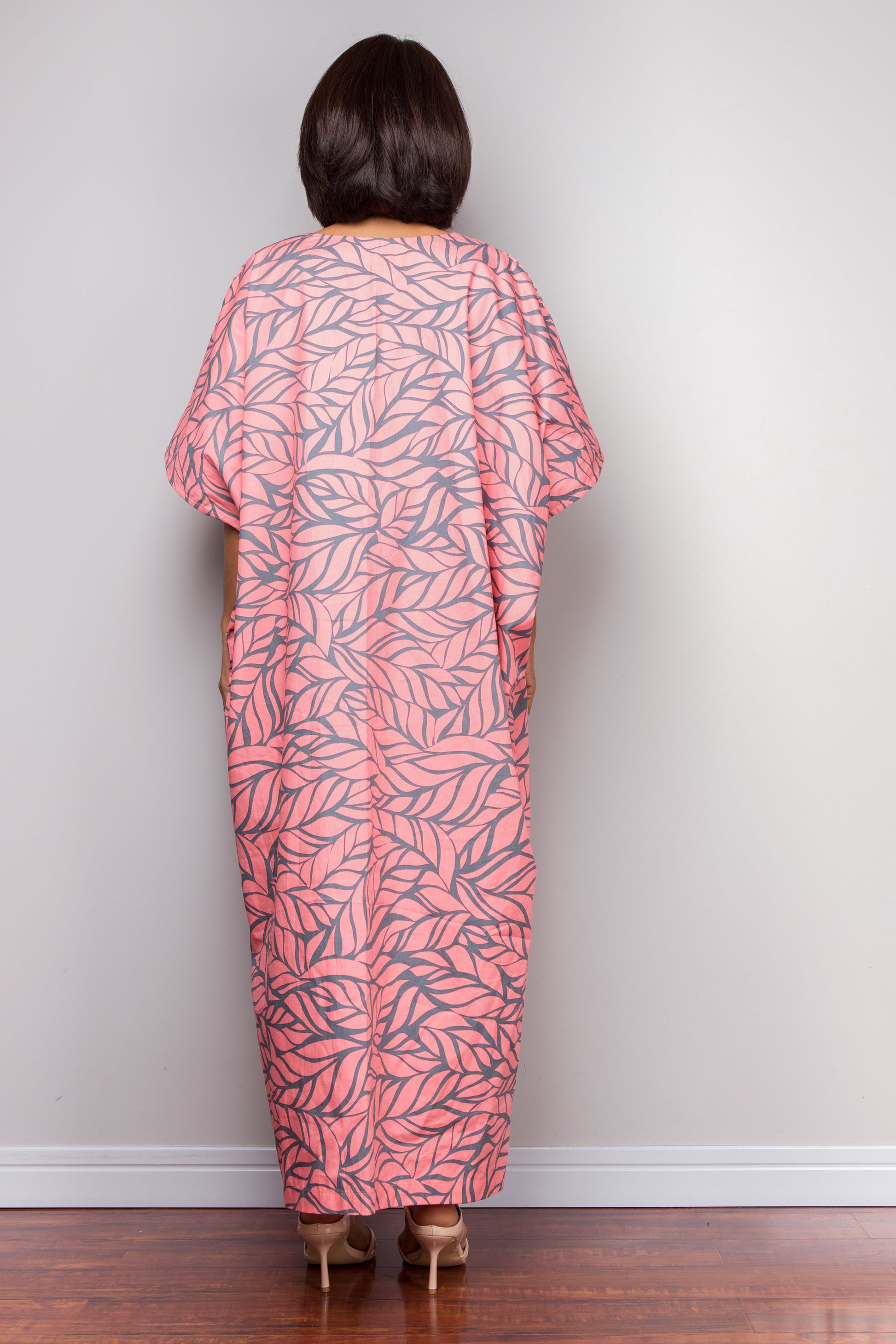 Petite woman wearing a pink color caftan dress against a plain background