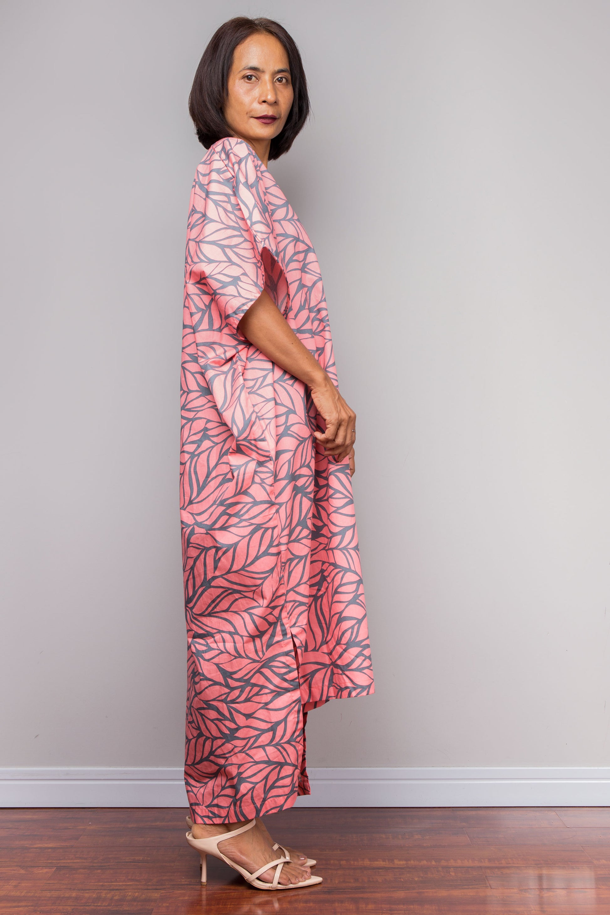 Woman wearing a pink leaf-patterned boho caftan against a plain background