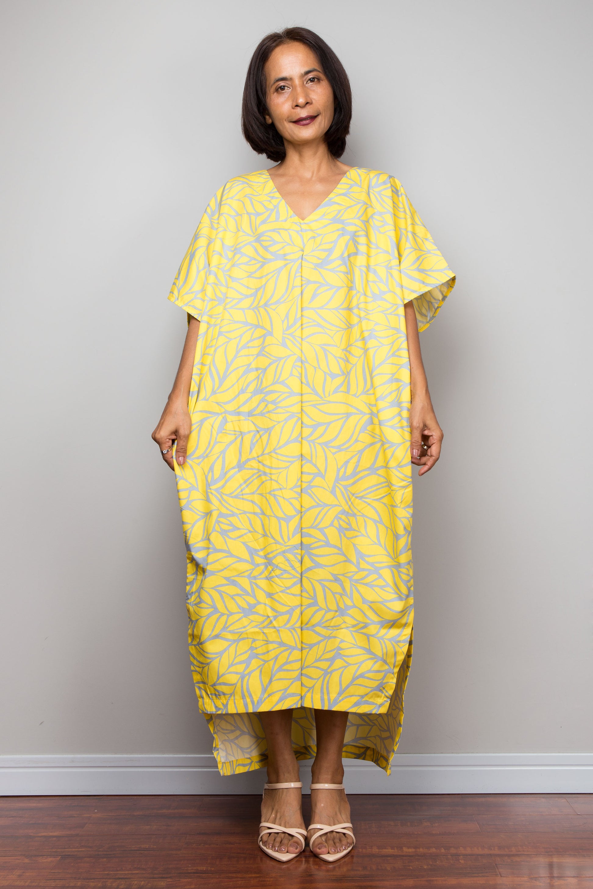 Woman wearing a yellow patterned cotton kaftan dress against a plain background