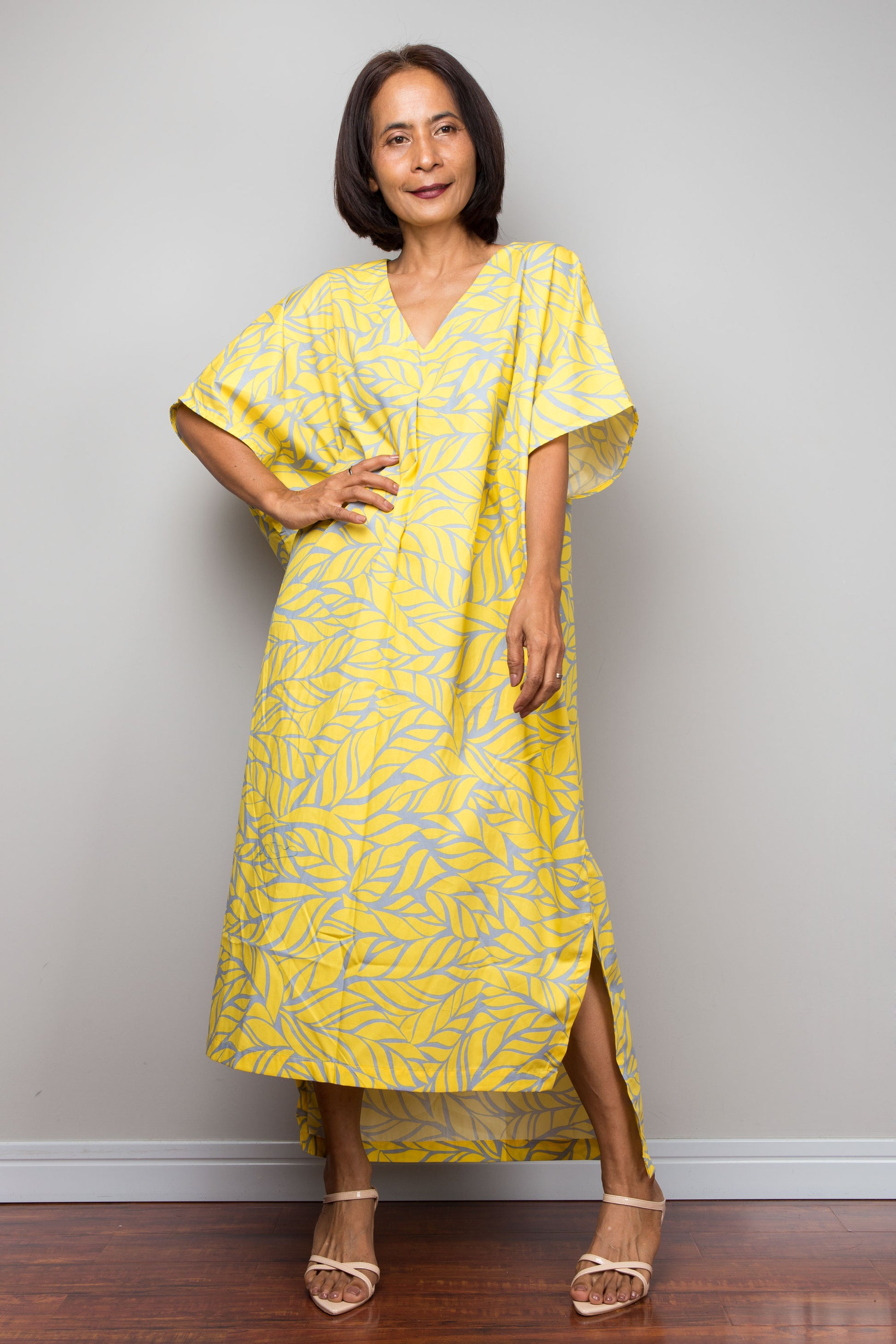 Woman wearing a yellow patterned dress against a plain background