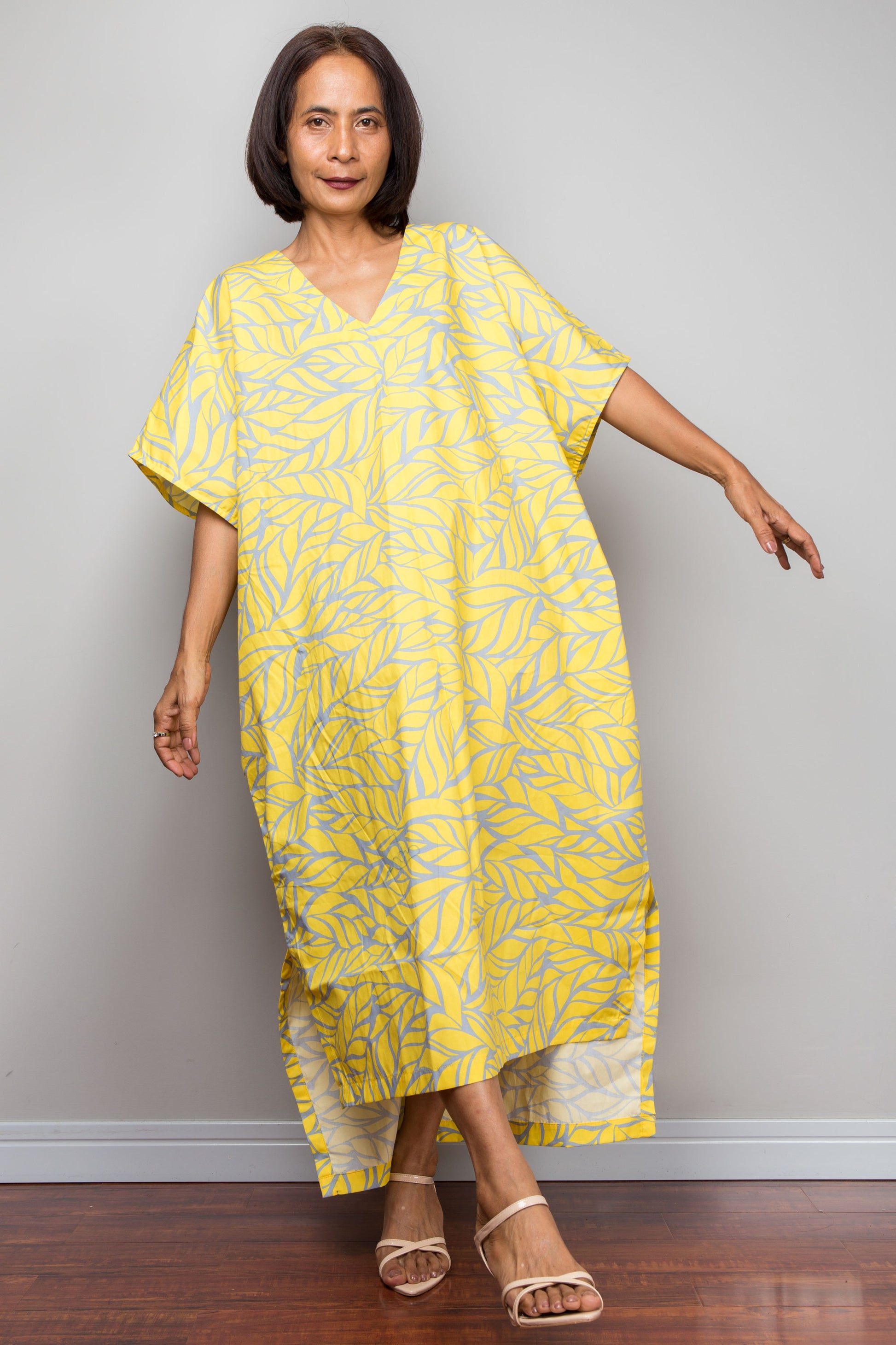 Woman wearing a yellow cotton caftan dress against a plain background
