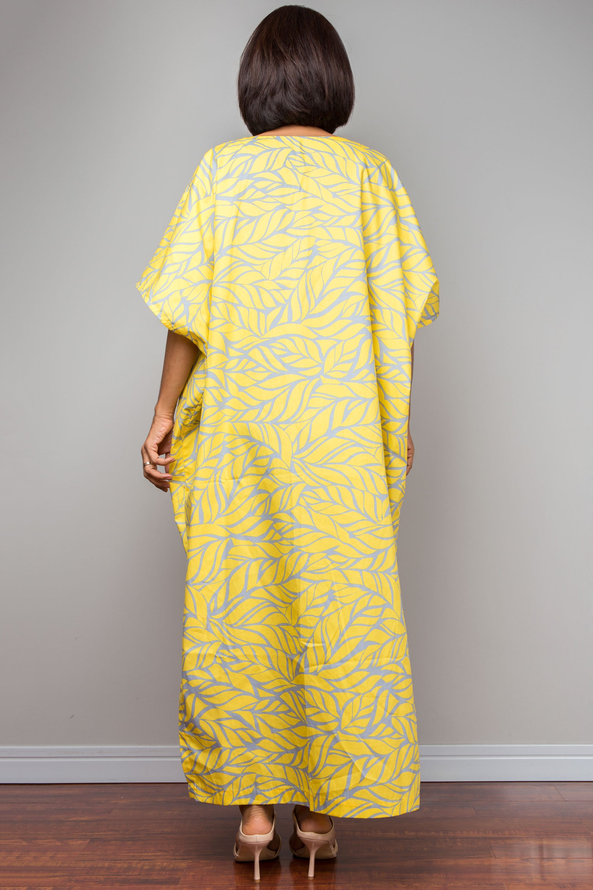 Woman wearing a yellow kaftan for petite dress against a plain background