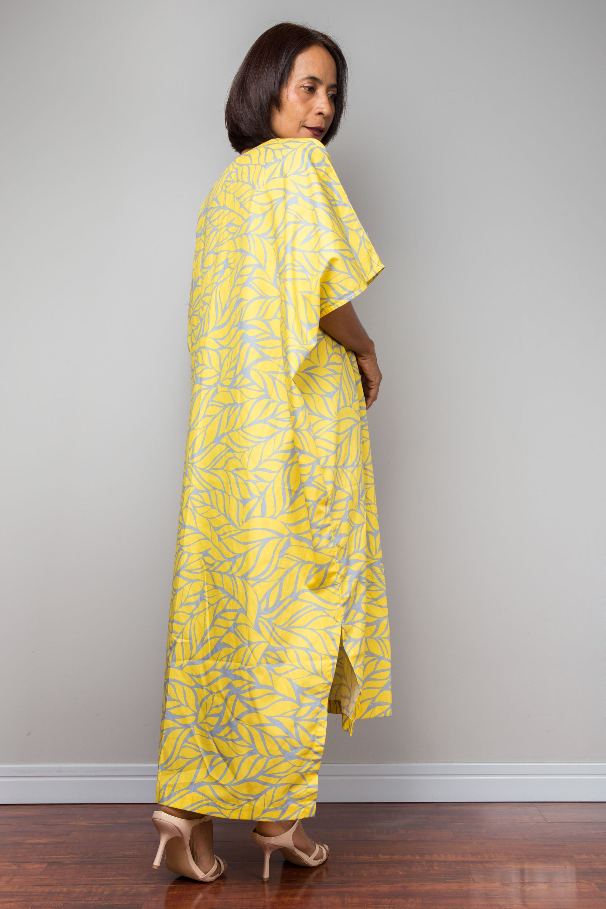 Woman wearing a yellow cotton kaftan dress against a plain background