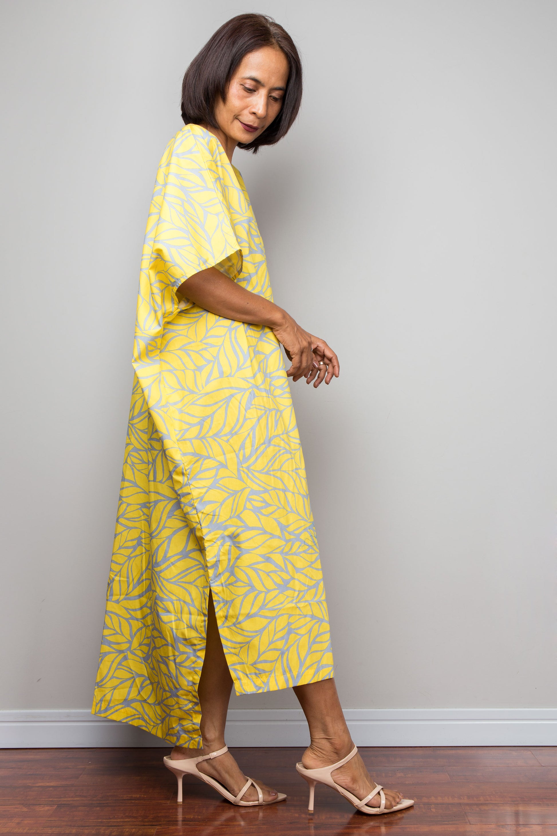 Petite woman wearing a yellow cotton caftan dress against a plain background