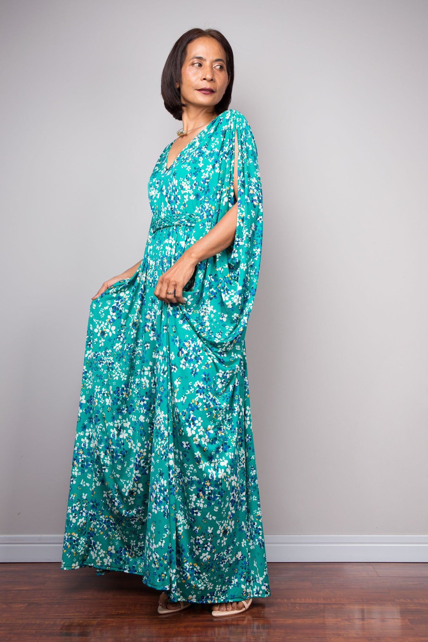Petite woman wearing a teal green floral kaftan against a plain background