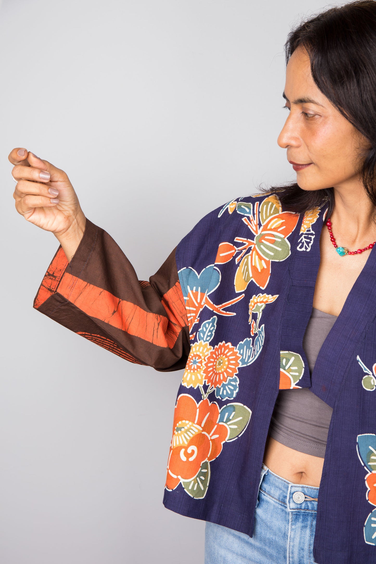 Woman wearing a colorful floral cotton kimono-style jacket against a plain background