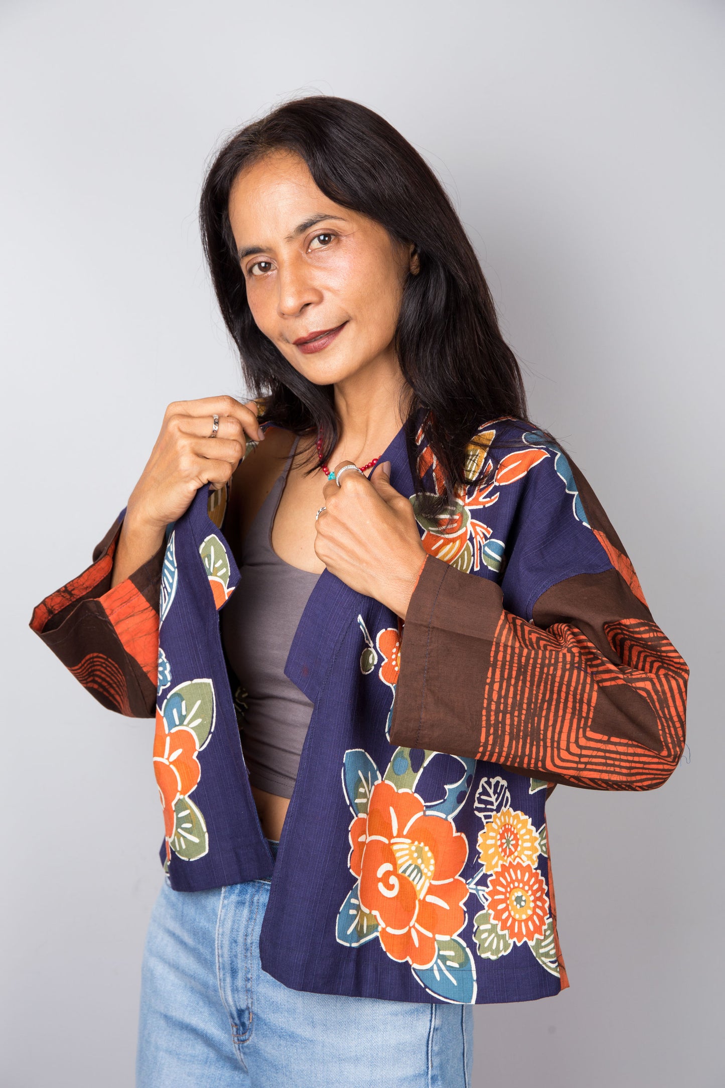 Woman wearing a colorful floral cotton kimono jacket against a plain background