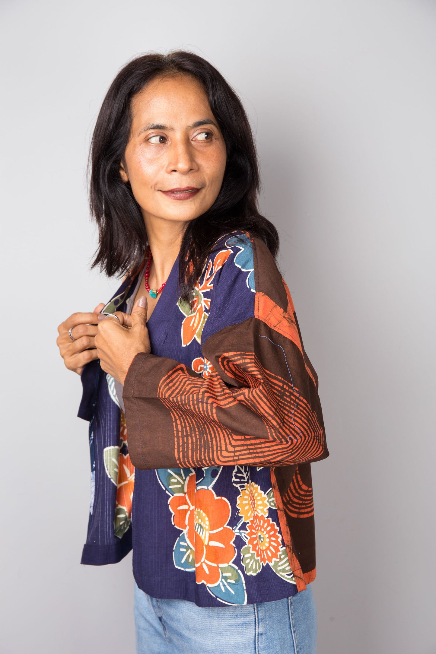 Woman wearing a colorful cotton kimono jacket against a plain background