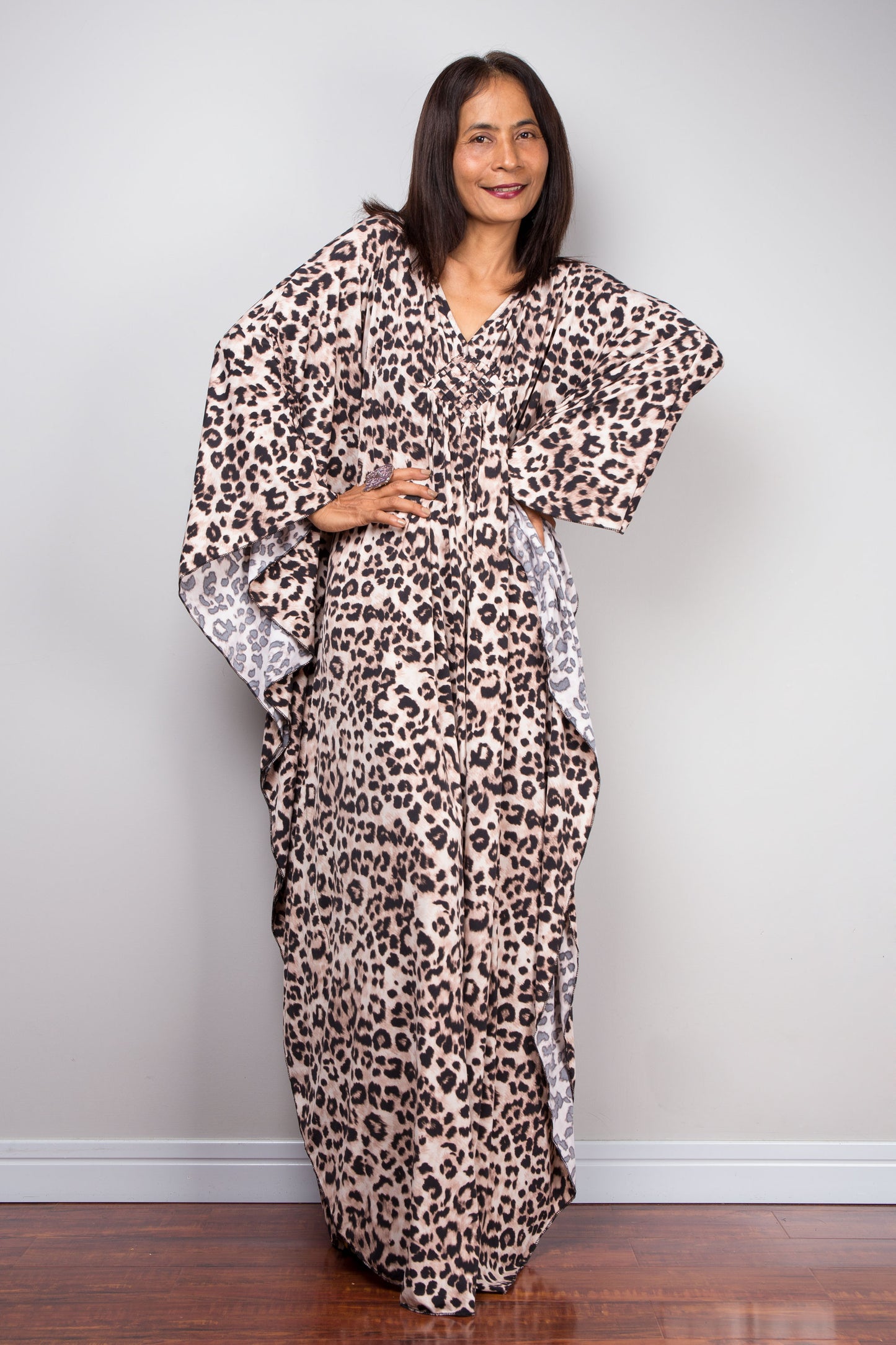 Elegant leopard print kaftan dress. The deep V-neckline highlights a diamond-shaped embroidery detail at the chest, with side slits and a flowing fit ideal for tropical casual style.