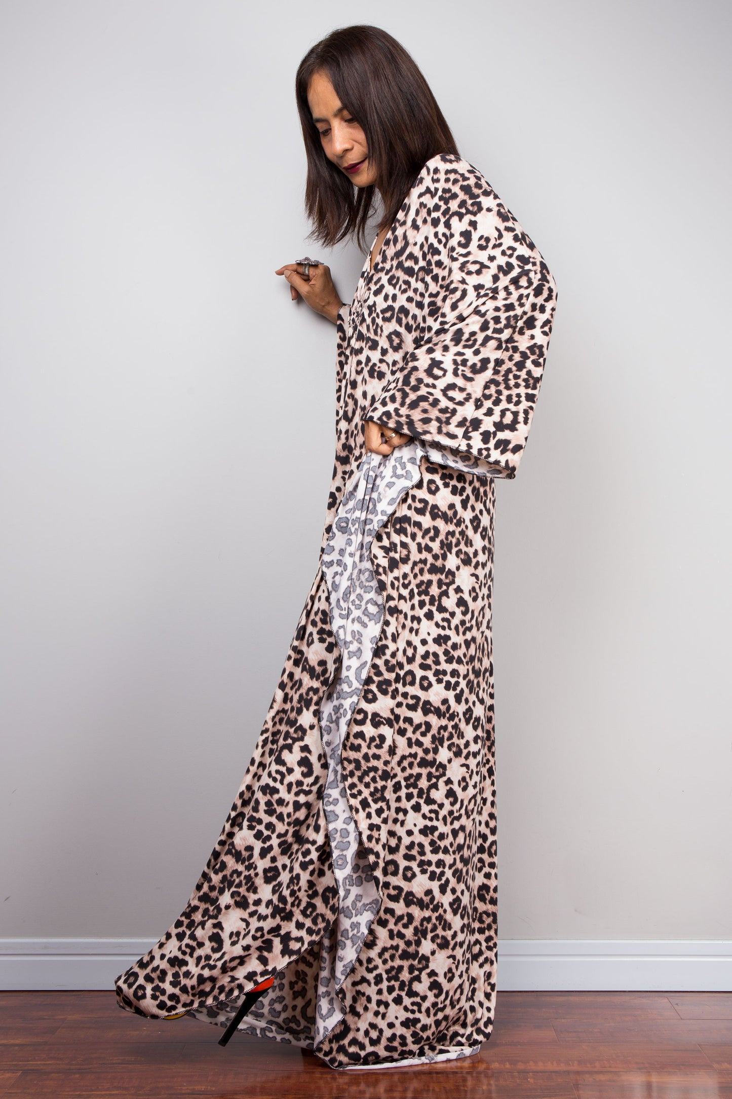 Leopard print kaftan dress by Nuichan. The dress features a deep V-neck with a diamond-shaped chest detail, side slits, and a flowing silhouette, ideal for tropical evenings or casual outings