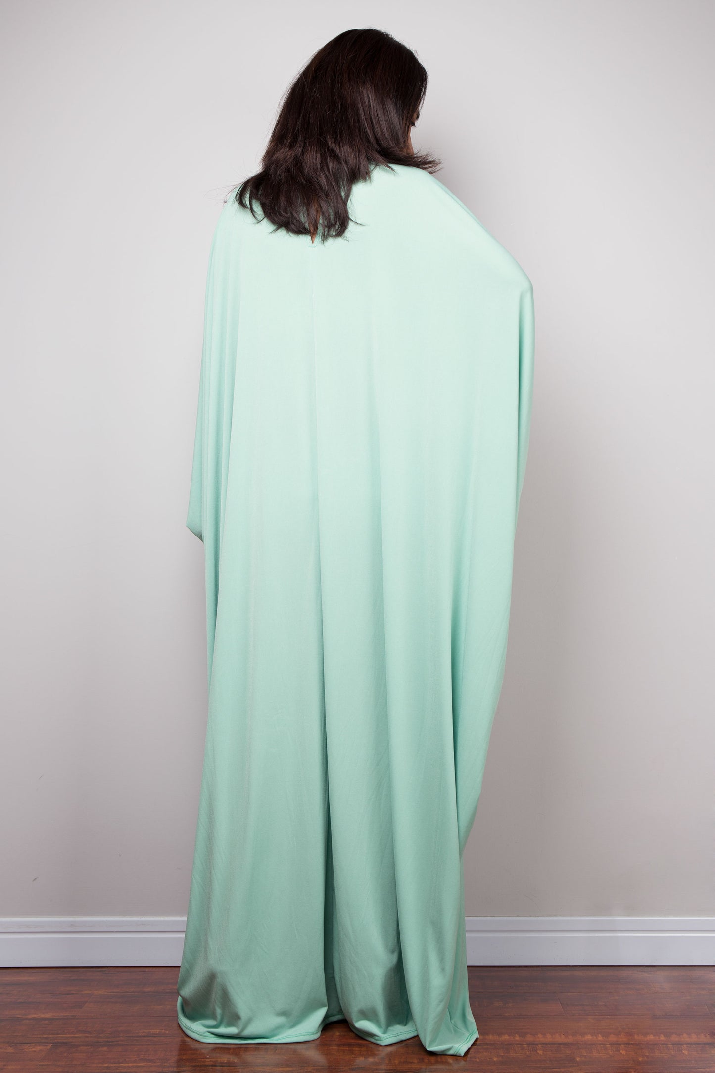Person wearing a light green kaftan dress against a plain background