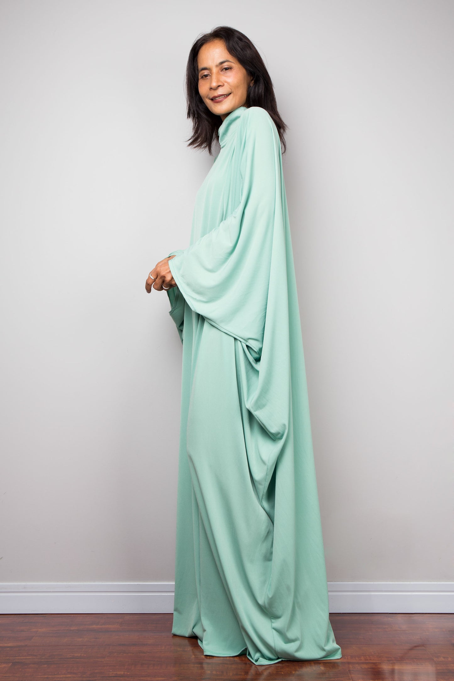 Woman wearing a mint green kaftan maxi dress against a plain background