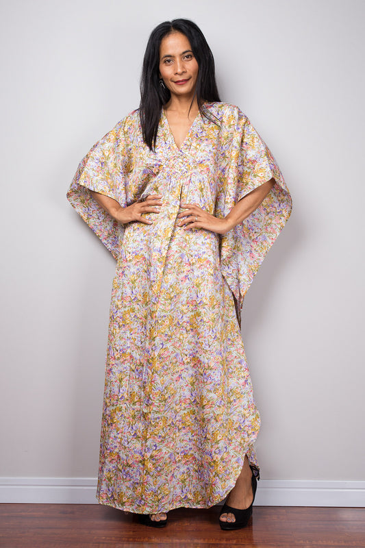 Woman wearing a floral caftan dress against a plain background