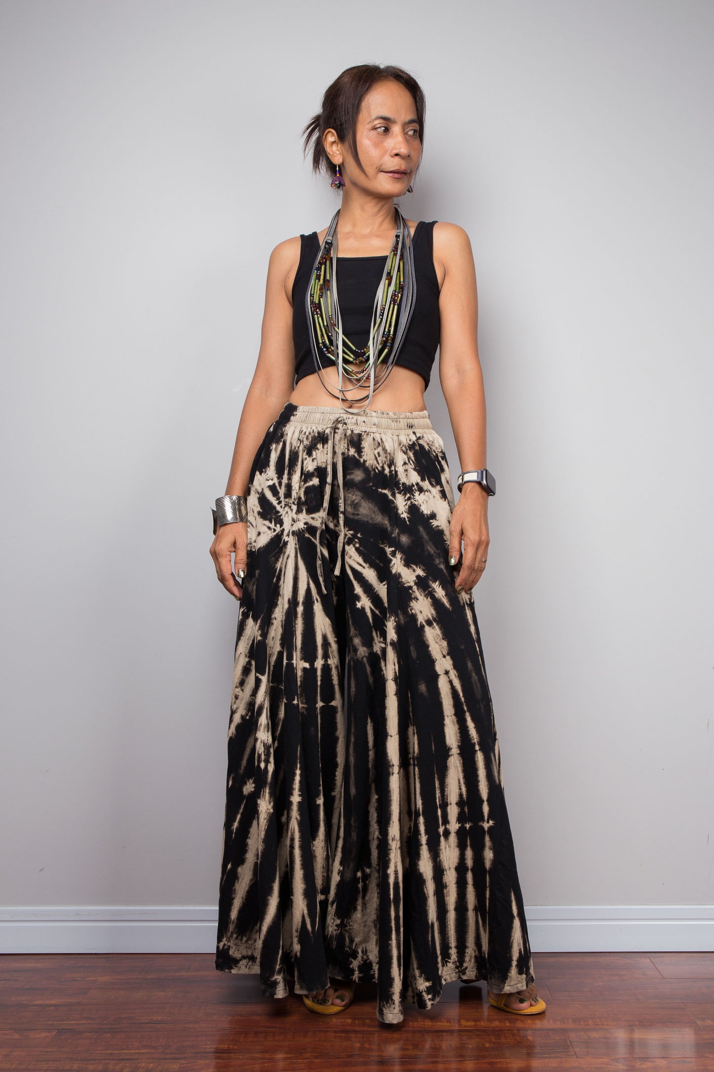 Woman wearing black and beige tie-dye pants against a plain background