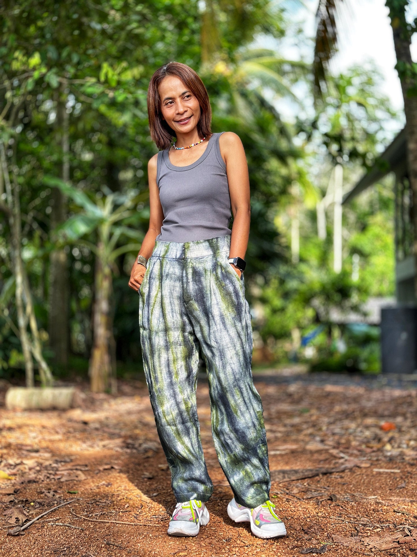 Woman wearing Nuichan tie-dye hemp pants with a gray-green design, perfect for festivals or casual outings. These handwoven boho trousers, made from Hmong hill tribe fabric.