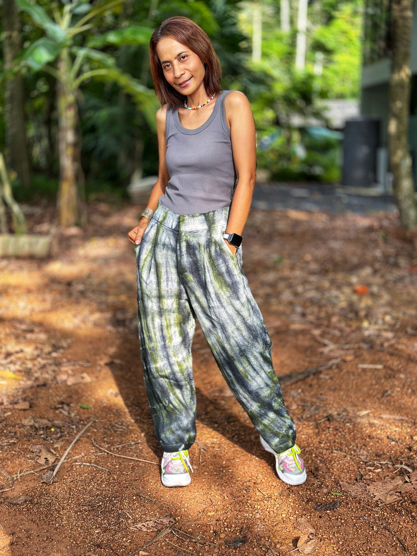 Model in Nuichan tie-dye hemp pants with a gray-green pattern.These sustainable boho trousers, made from handwoven Hmong fabric, exude a free-spirited, nature-inspired vibe