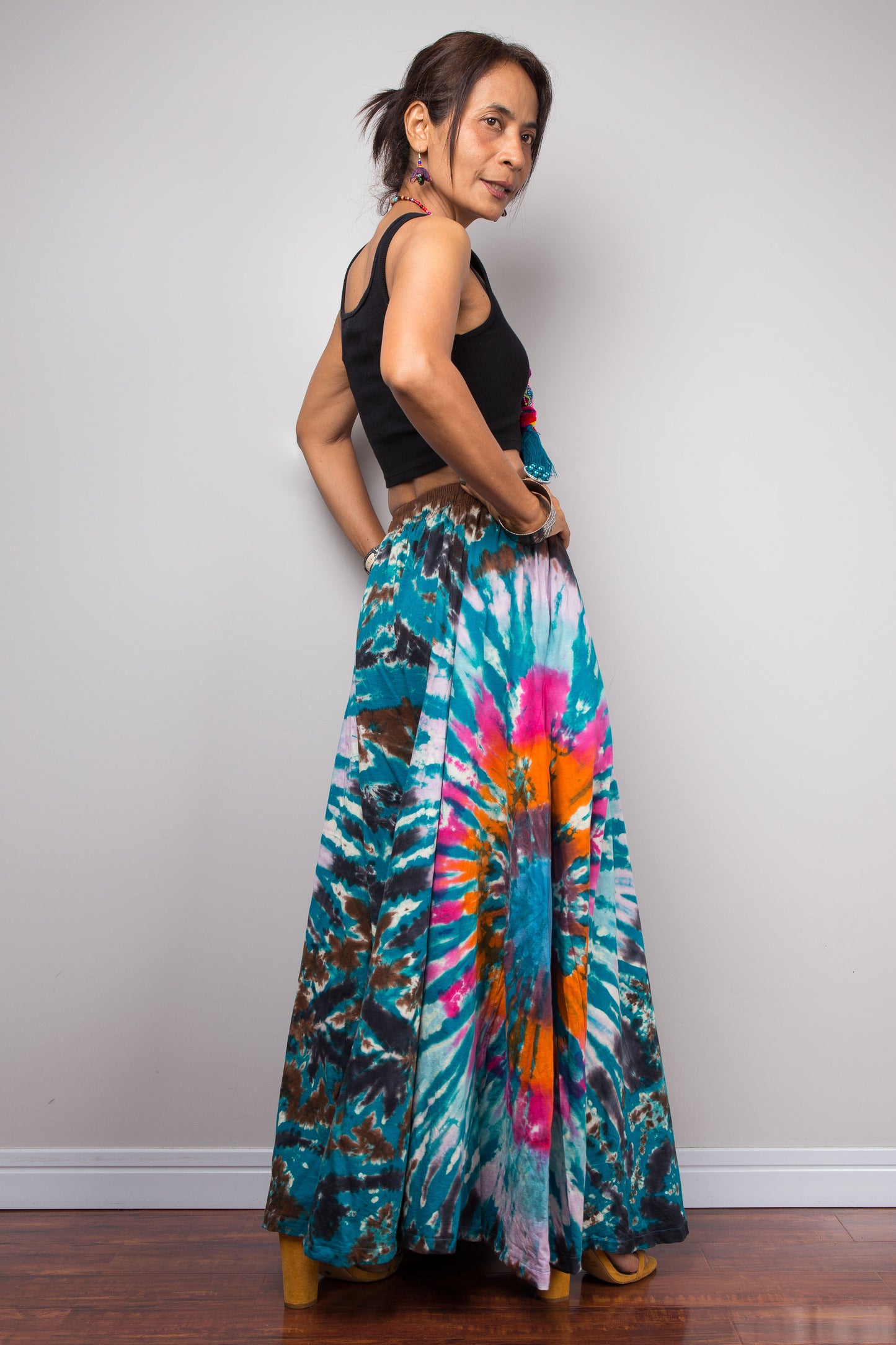 Full-length three-quarter view of a model in the Nuichan multicolour tie dye wide leg palazzo pants, highlighting the complete floor-grazing length, dramatic wide leg volume, and the vivid organic freeform tie dye composition in teal turquoise hot pink orange and chocolate brown