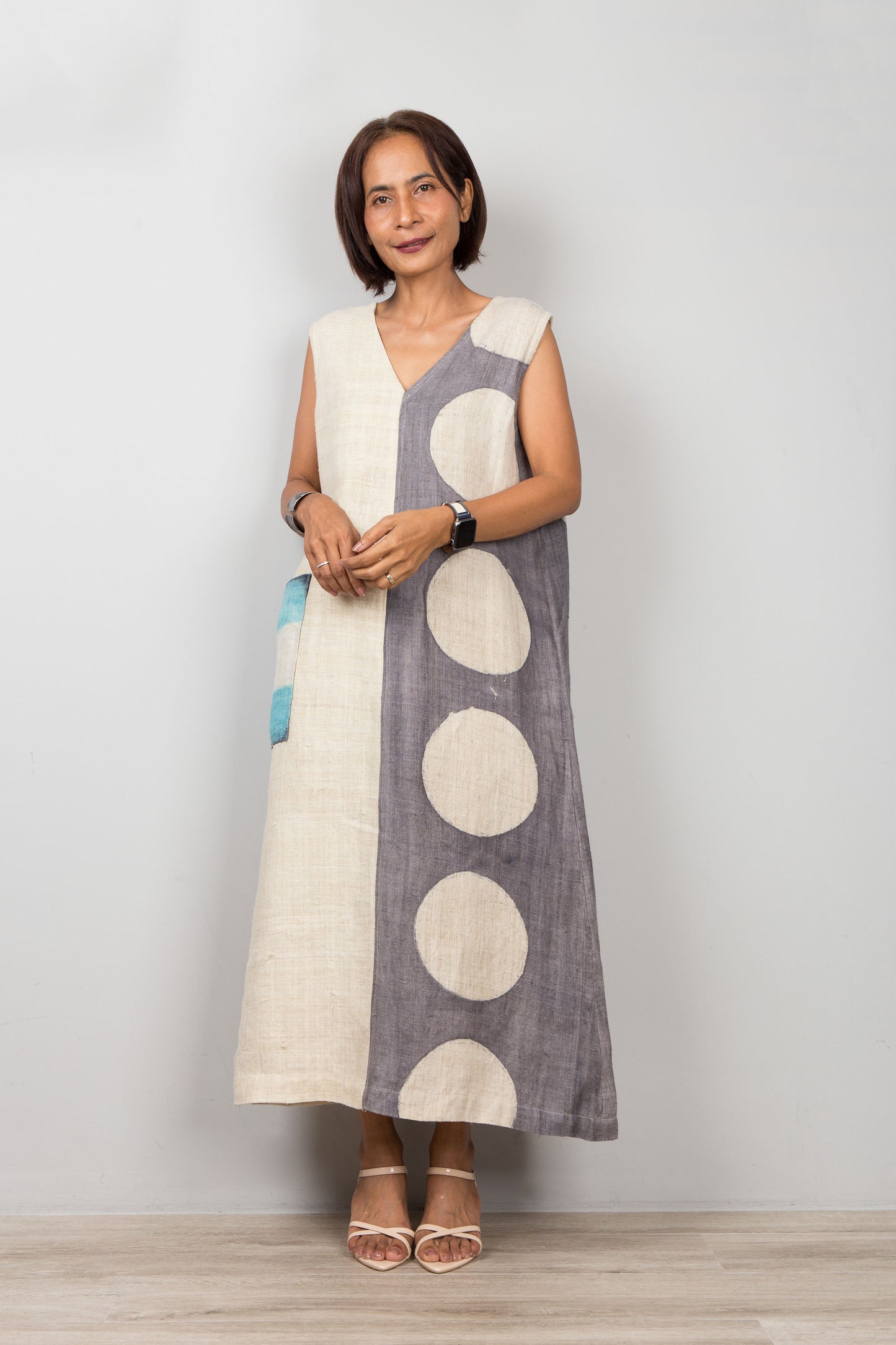 Woman wearing a sleeveless dress with polka dot patterns on a plain background