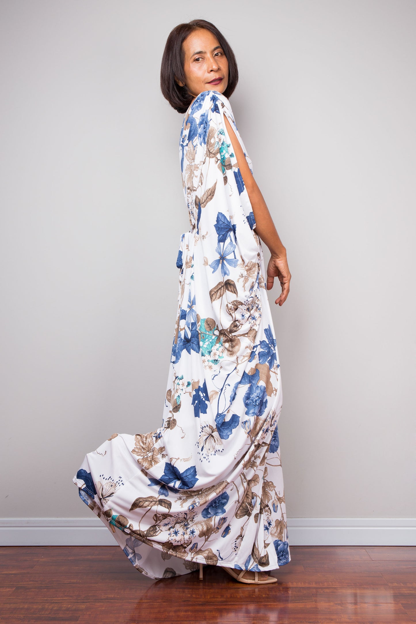 Woman wearing a floral caftan maxi dress against a plain background