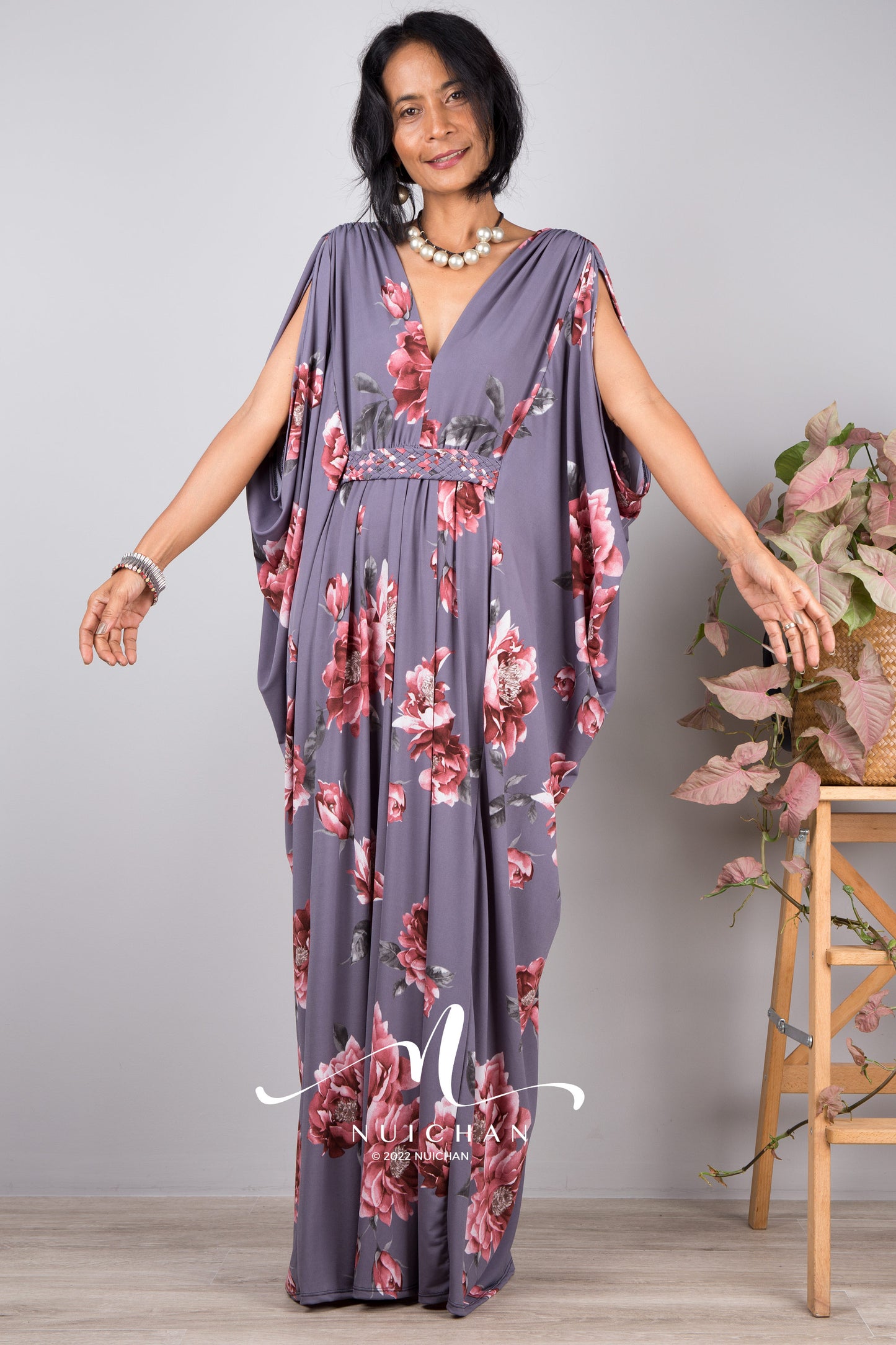 Woman wearing a grey maxi dress with flower print. Petite caftan with v neckline