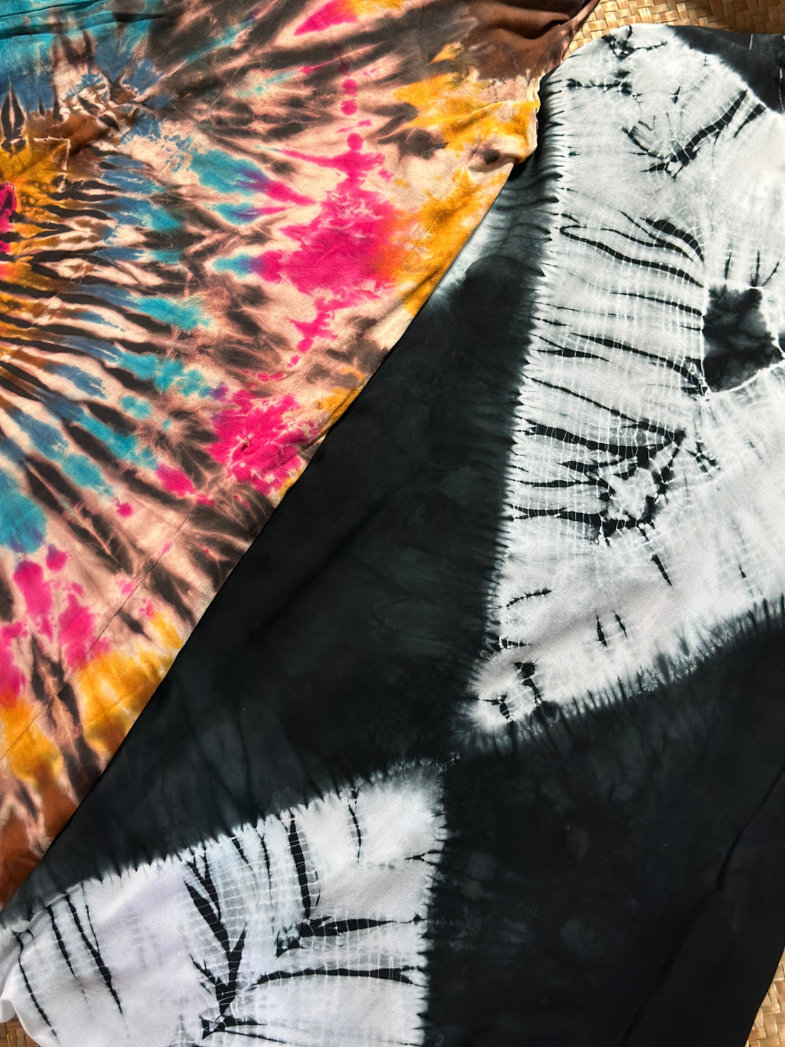 Side by side comparison of multicolor swirl tie dye fabric and black and white shibori fabric, showing the visual difference between the two dyeing techniques