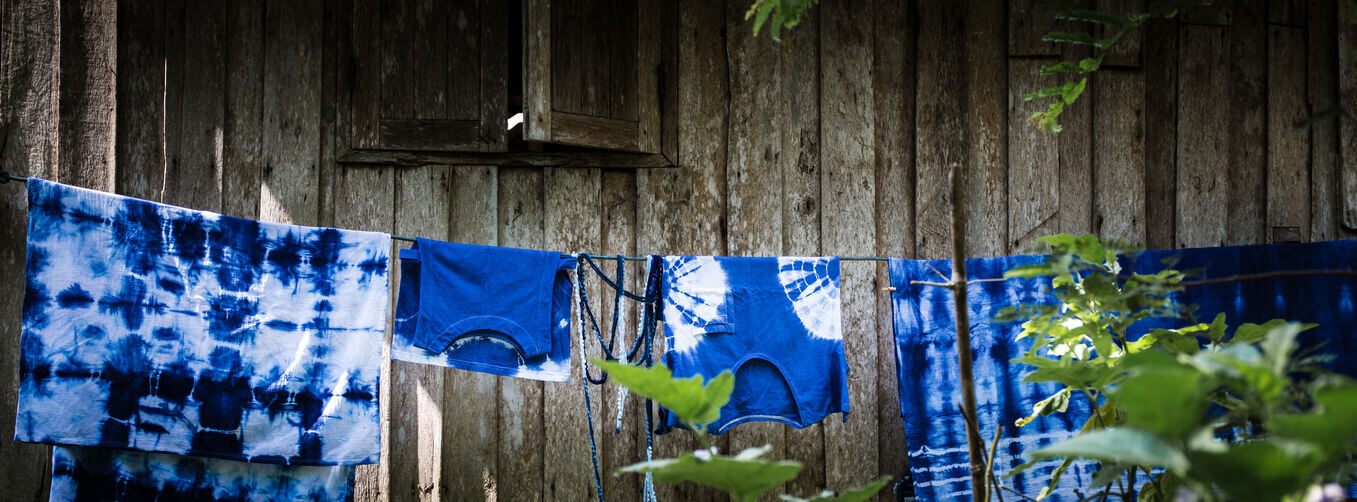 Various pieces of indigo shibori hanging to dry on a washing line.
