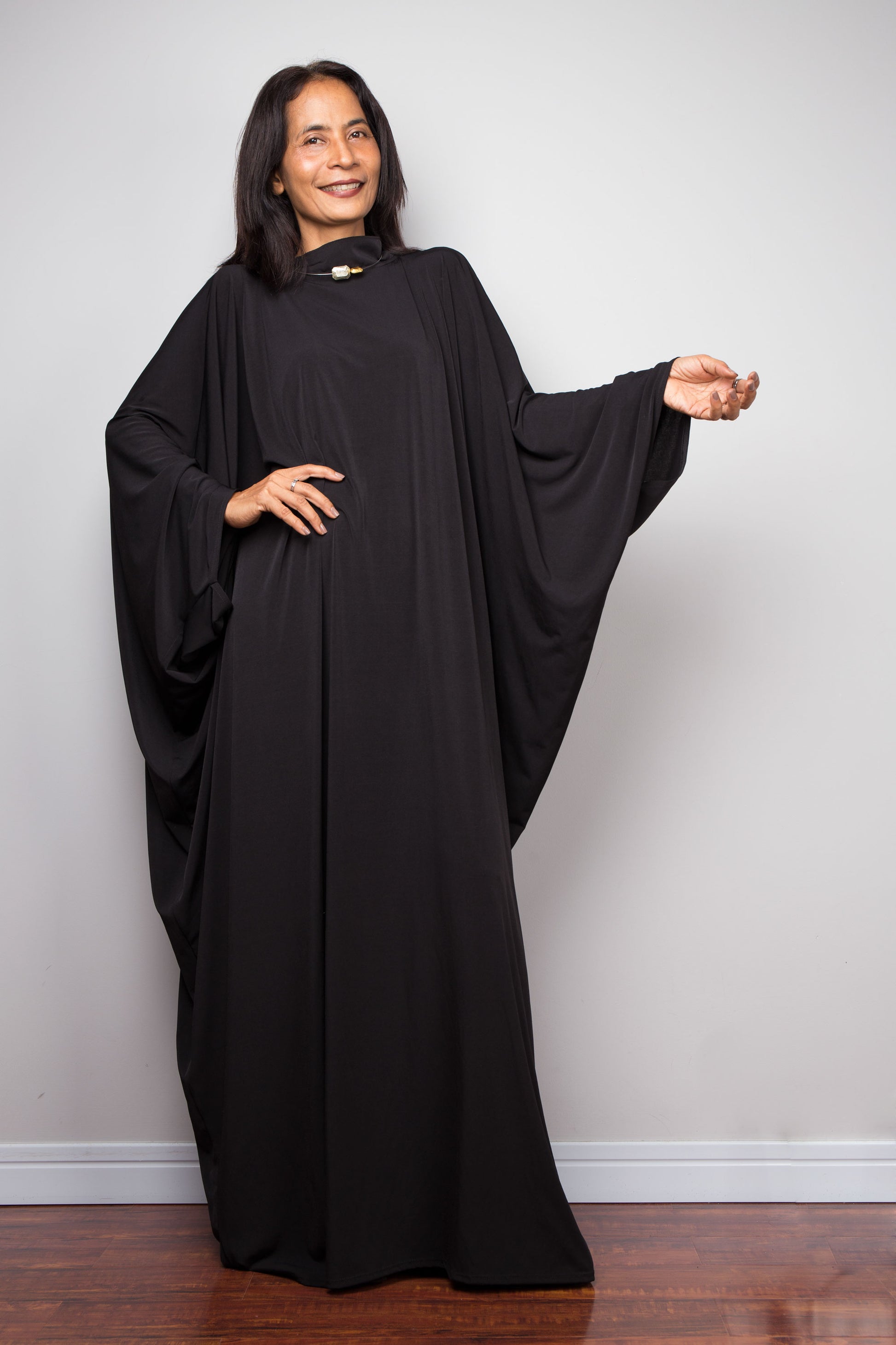 Woman wearing a black abaya standing against a plain background.  Large black dress by Nuichan