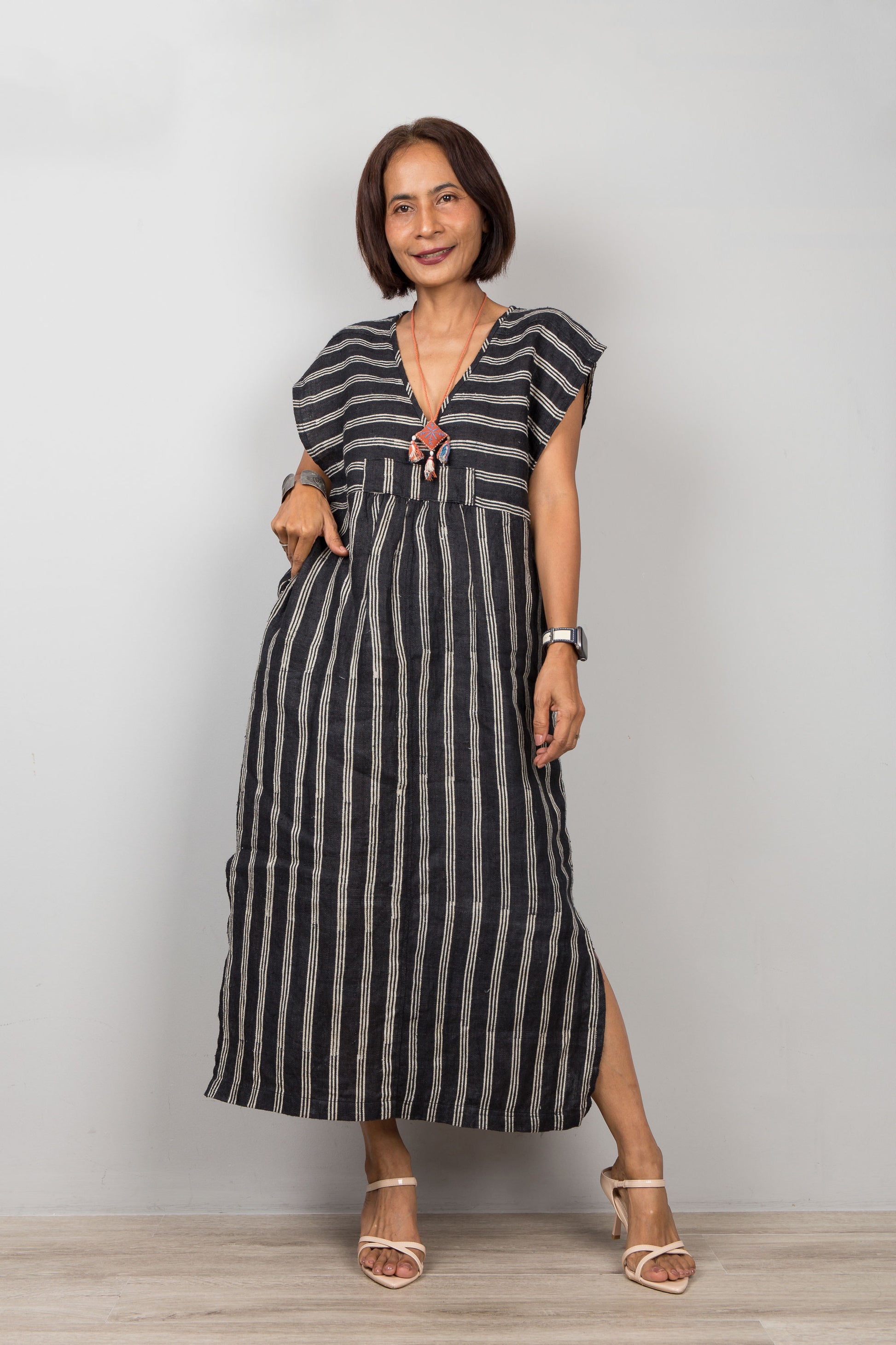 Woman wearing a black and white striped kaftan with short sleeves against a plain background