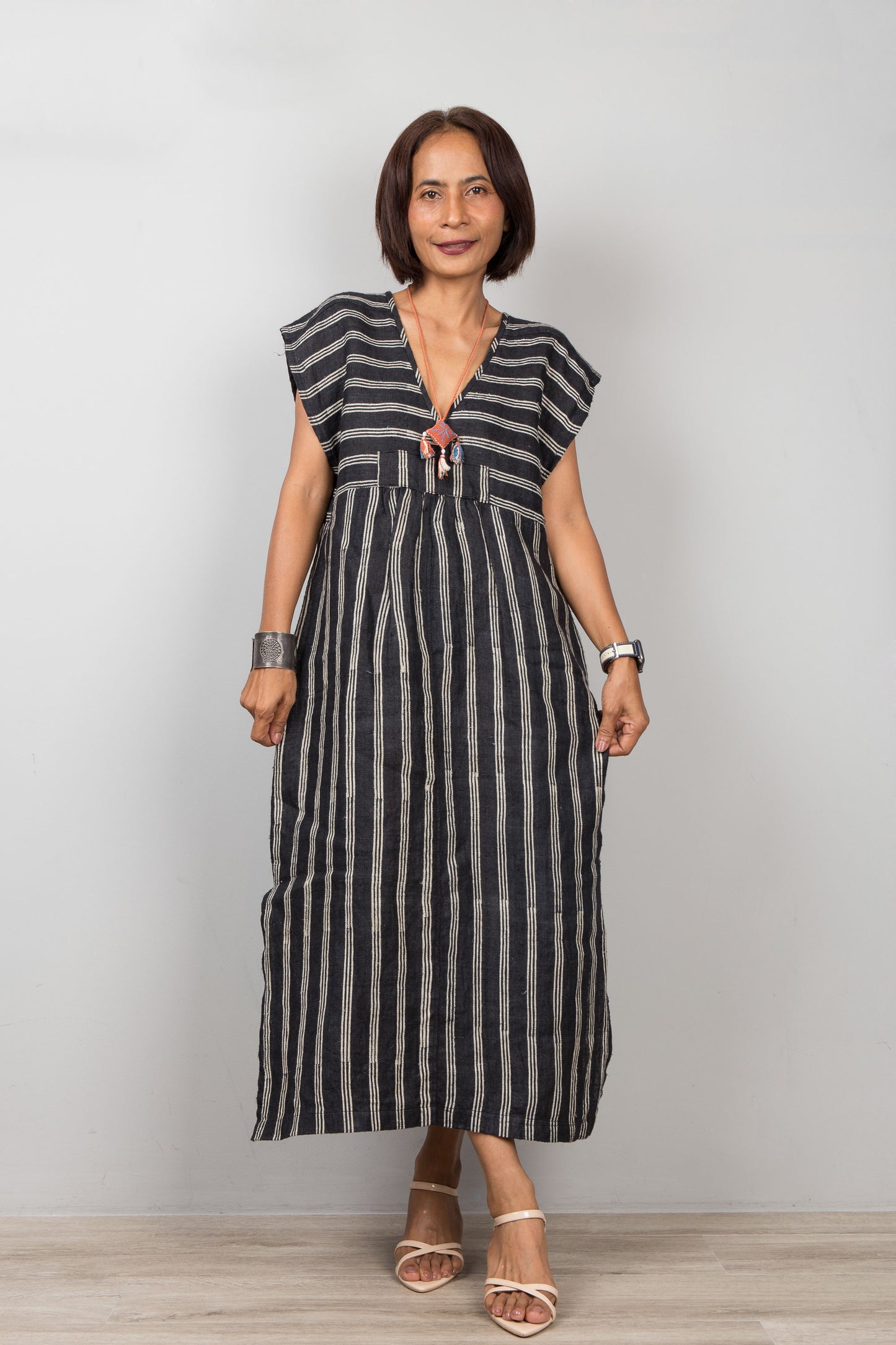 Woman wearing a black kaftan with white stripes against a plain background