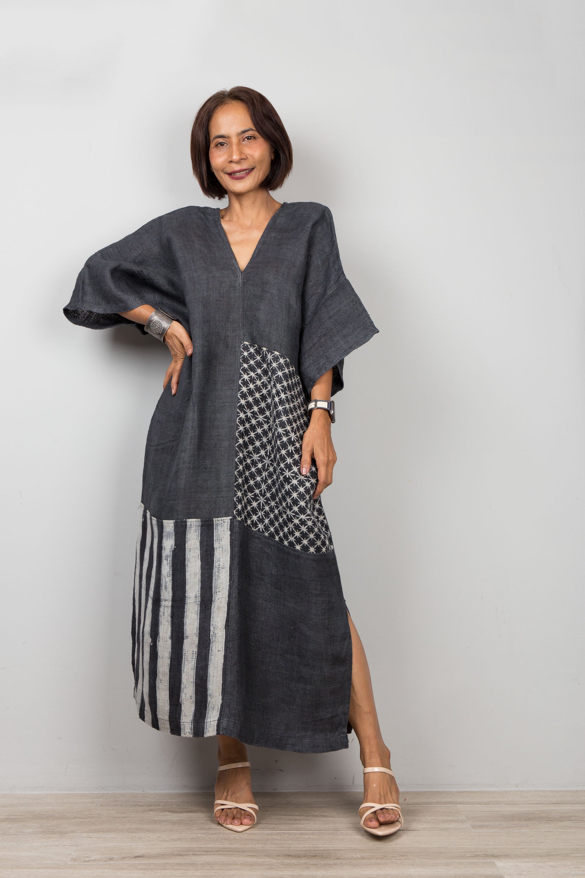Woman wearing a black patchwork hemp dress with a plain background